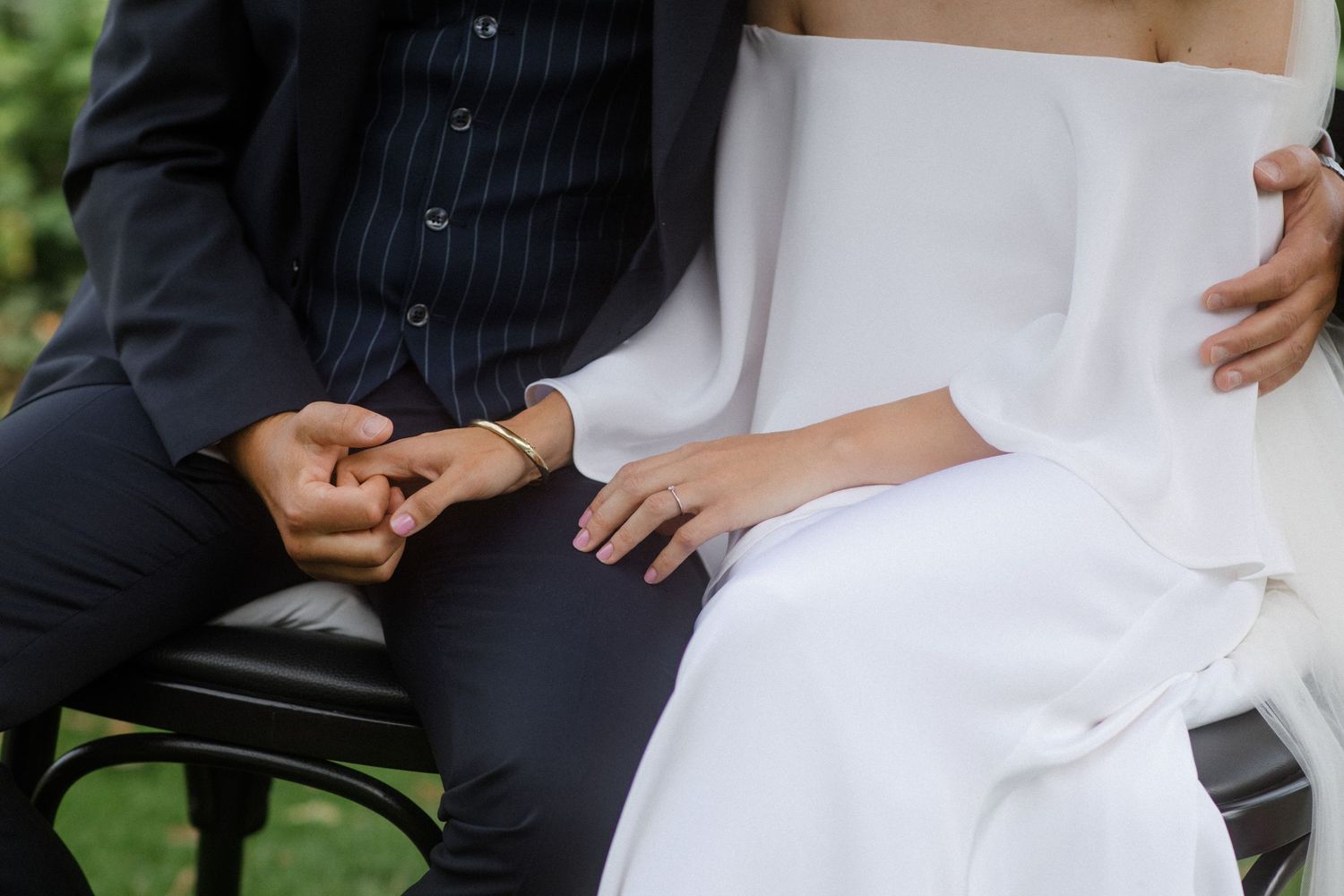 Close-up of couple's hands and formal attire while sitting together.