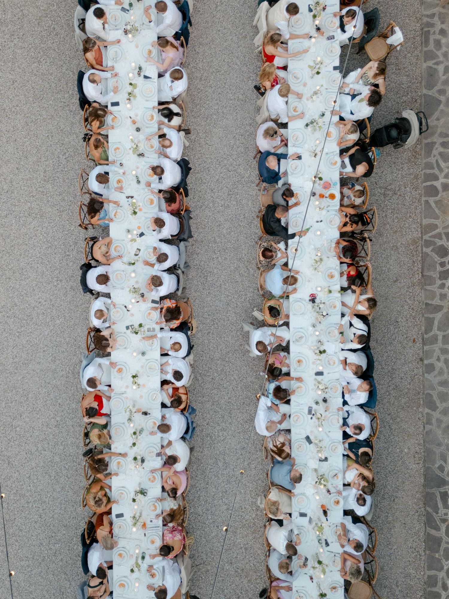Bird's eye view of long dining tables arranged for an outdoor wedding reception.