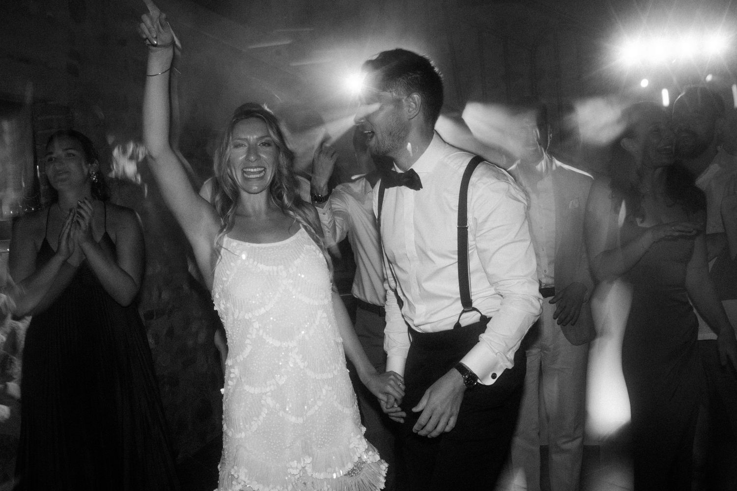 Party guests dancing under atmospheric lighting at a wedding reception.