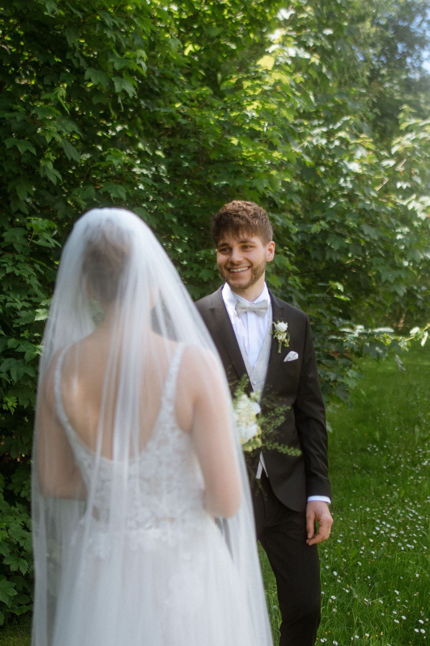 A joyful first look moment between newlyweds in a verdant garden setting.