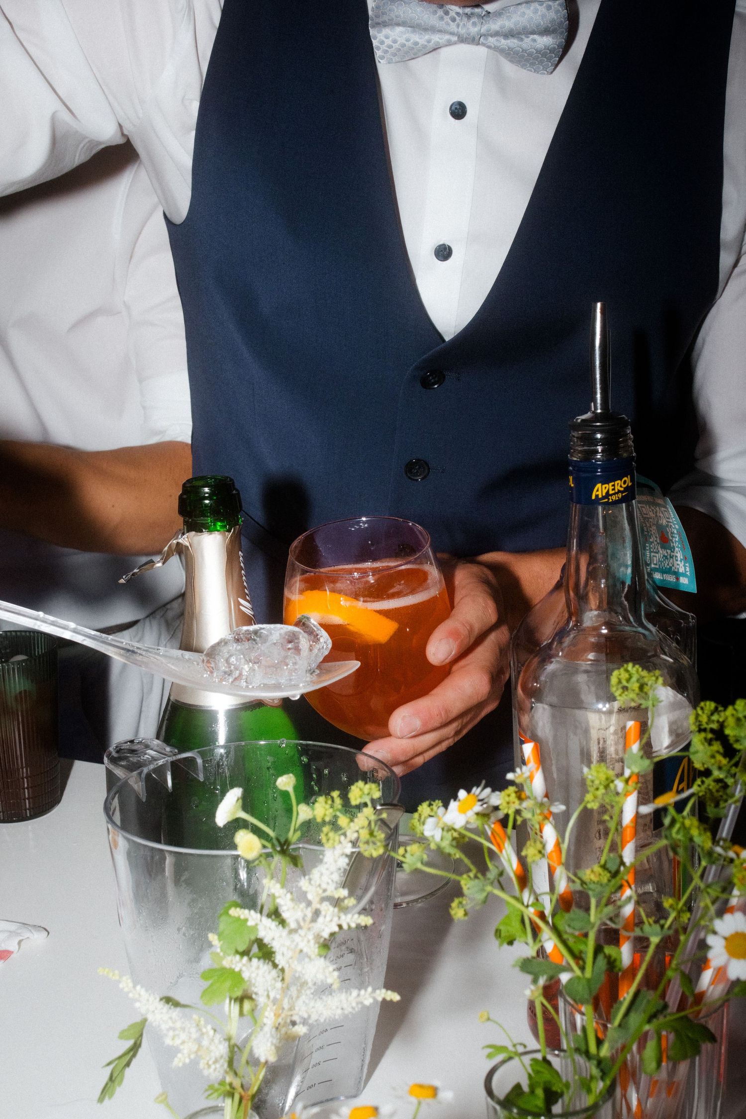 Close-up of formal attire and drinks being served with floral decorations at an event.
