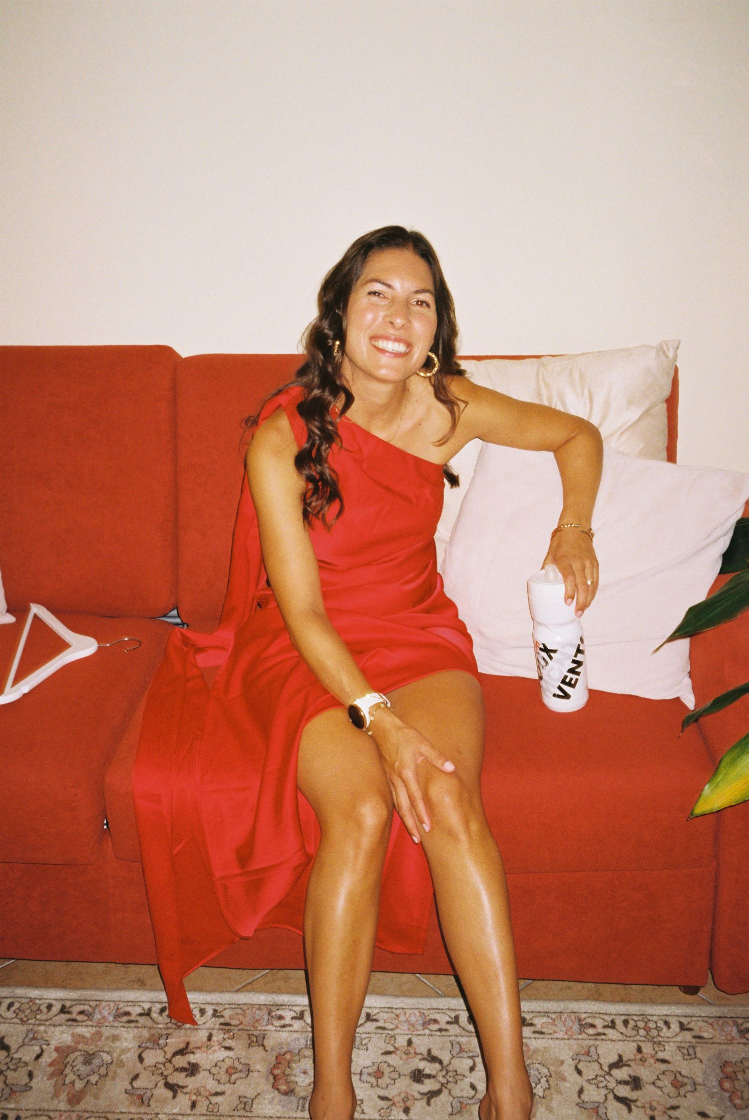 A series of candid photos showing someone in a red dress lounging on a red couch against a white wall.