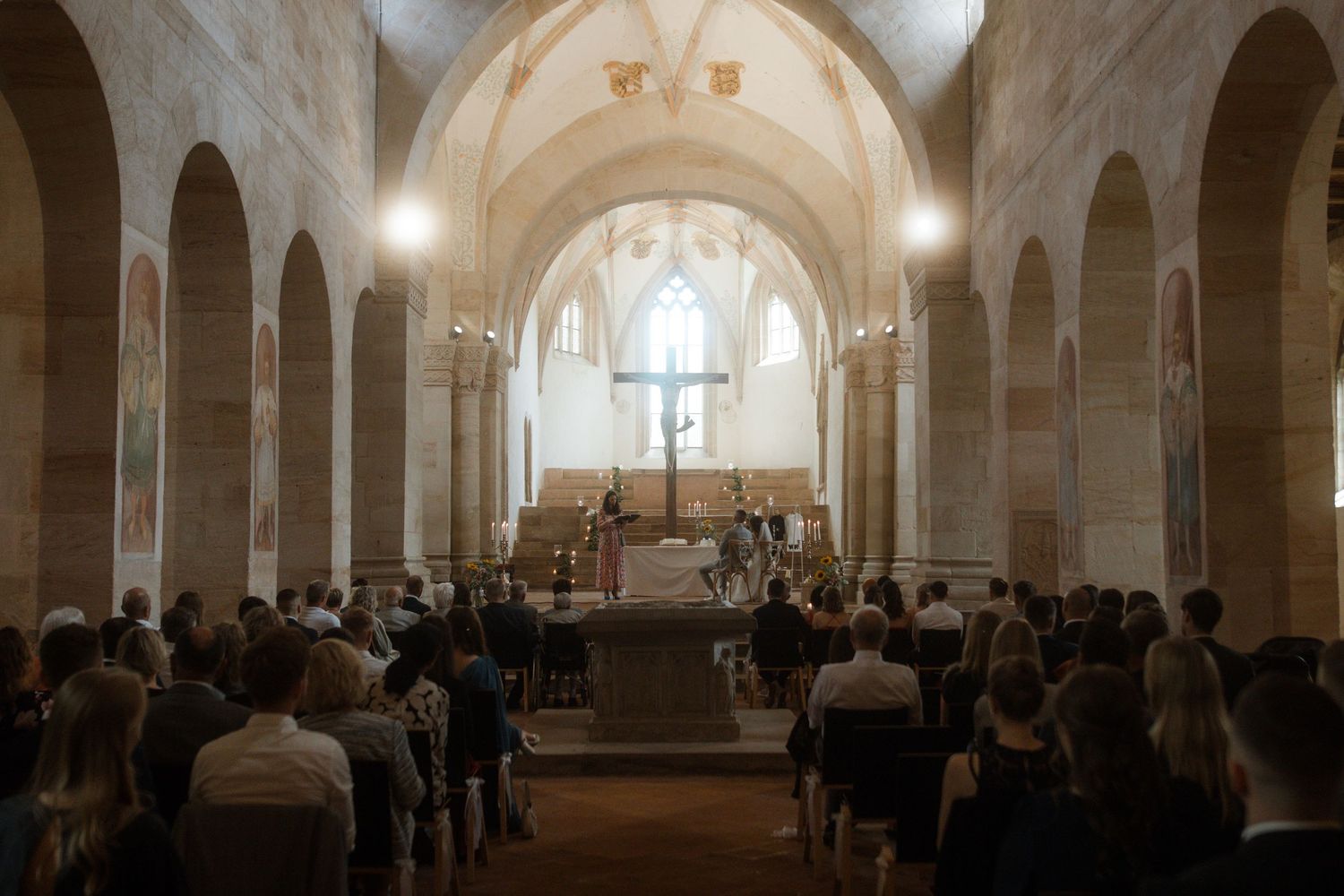 Wedding ceremony in a historic stone church with vaulted ceilings and gathered guests.
