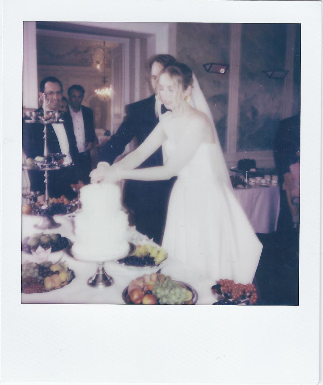 A white tiered wedding cake displayed on an elegant table with other desserts.