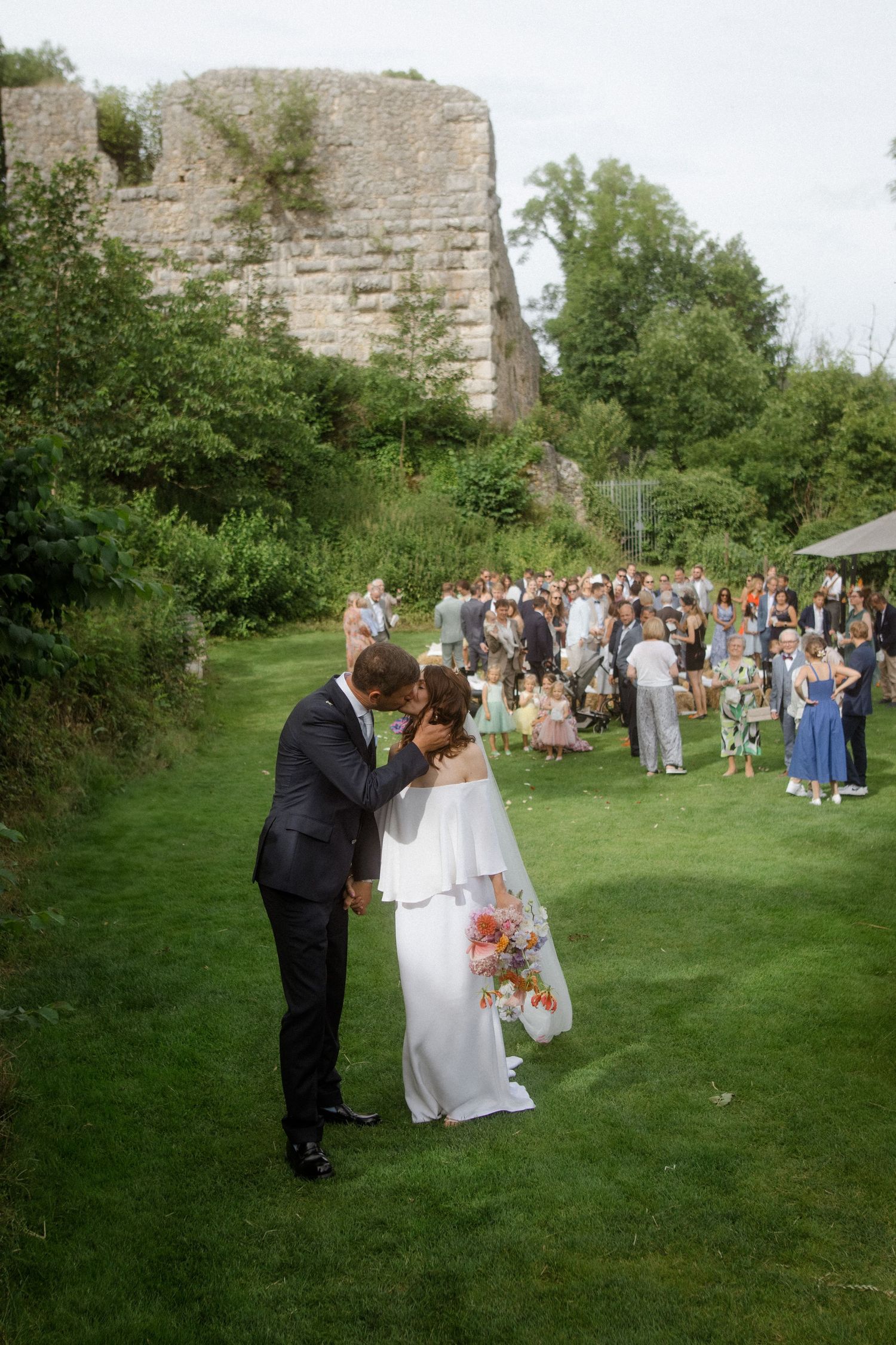 Couple shares a romantic moment at their outdoor wedding ceremony in front of historic stone ruins.