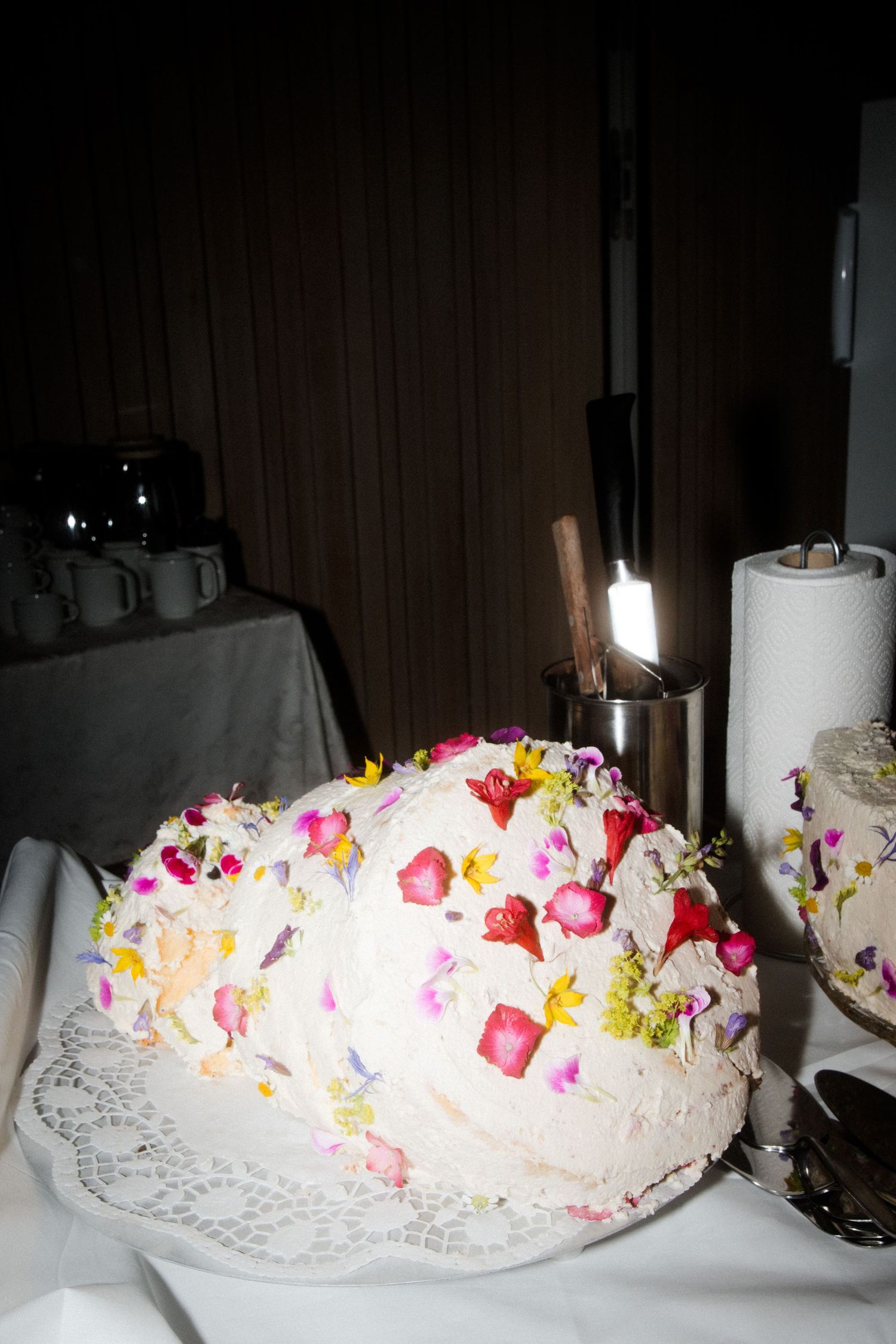 A beautifully decorated white wedding cake with colorful floral decorations on a table.