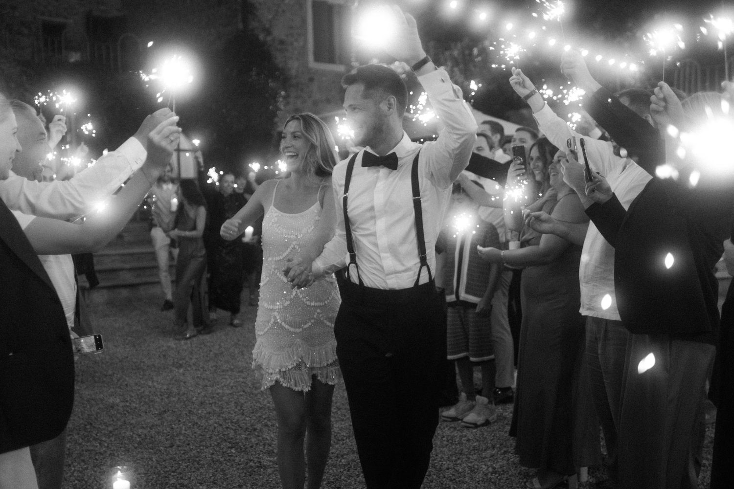 Wedding guests create a magical sparkler tunnel during an evening celebration.