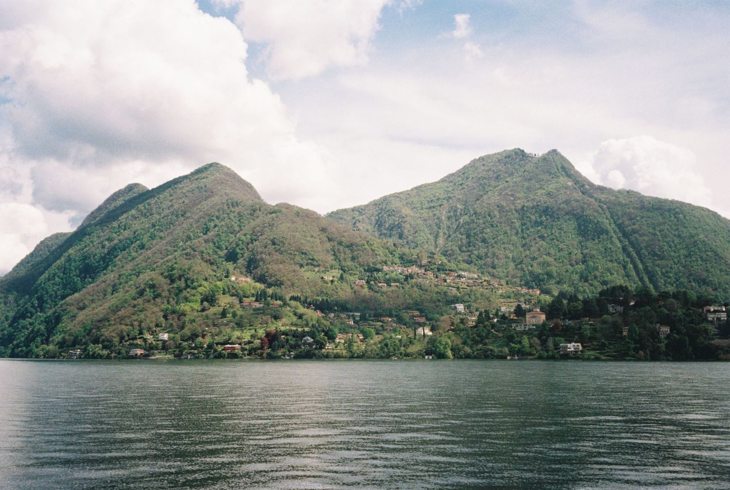 Scenic mountain range overlooking a serene lake with cloudy skies in the background.