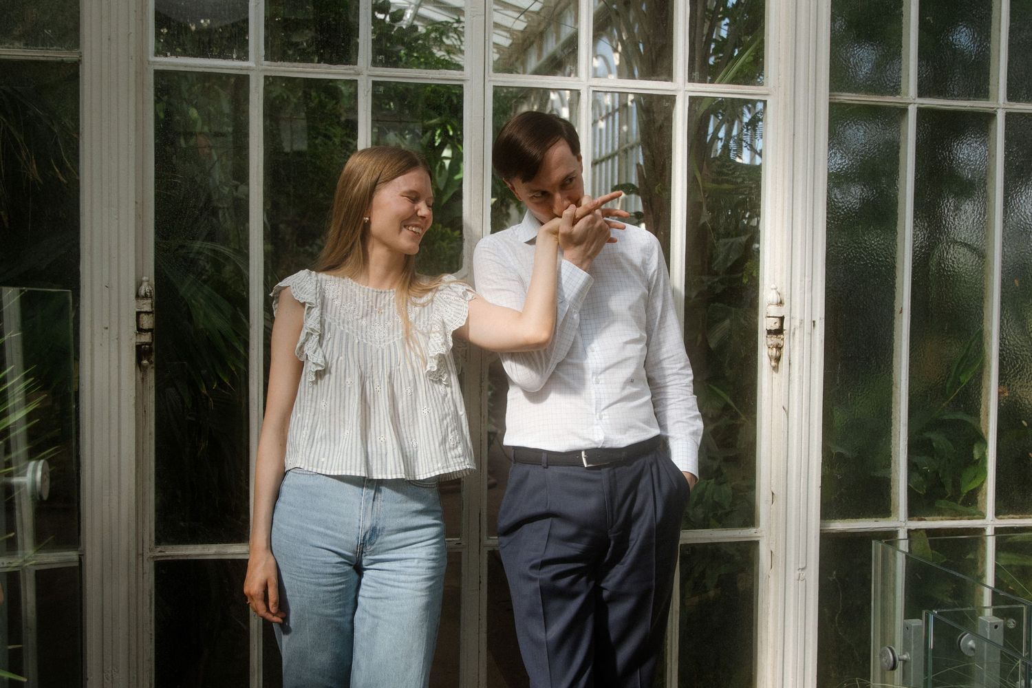 Romantic greenhouse photoshoot with couples among tropical plants and natural lighting.