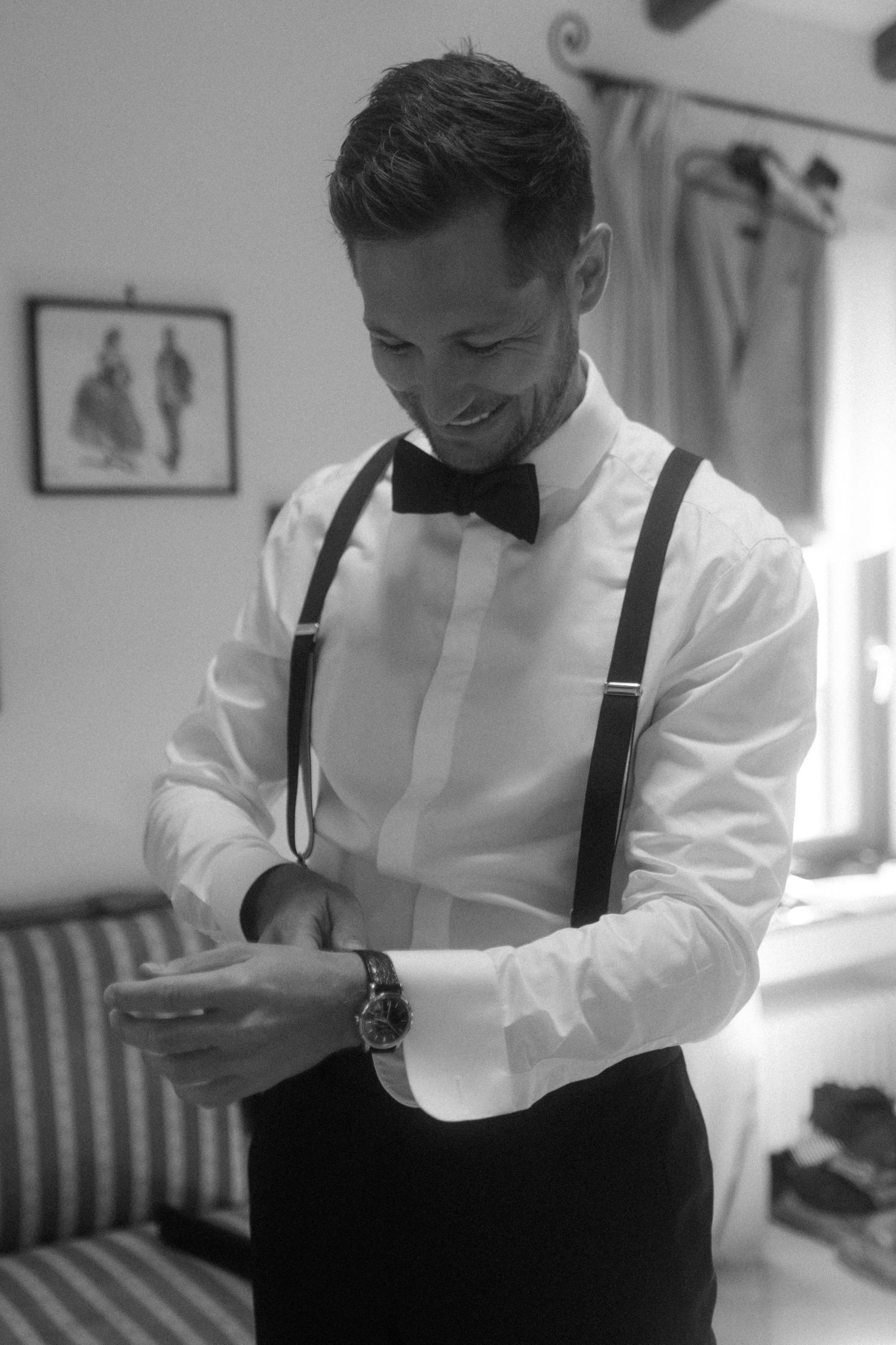 A formal outfit with suspenders and bow tie being adjusted.