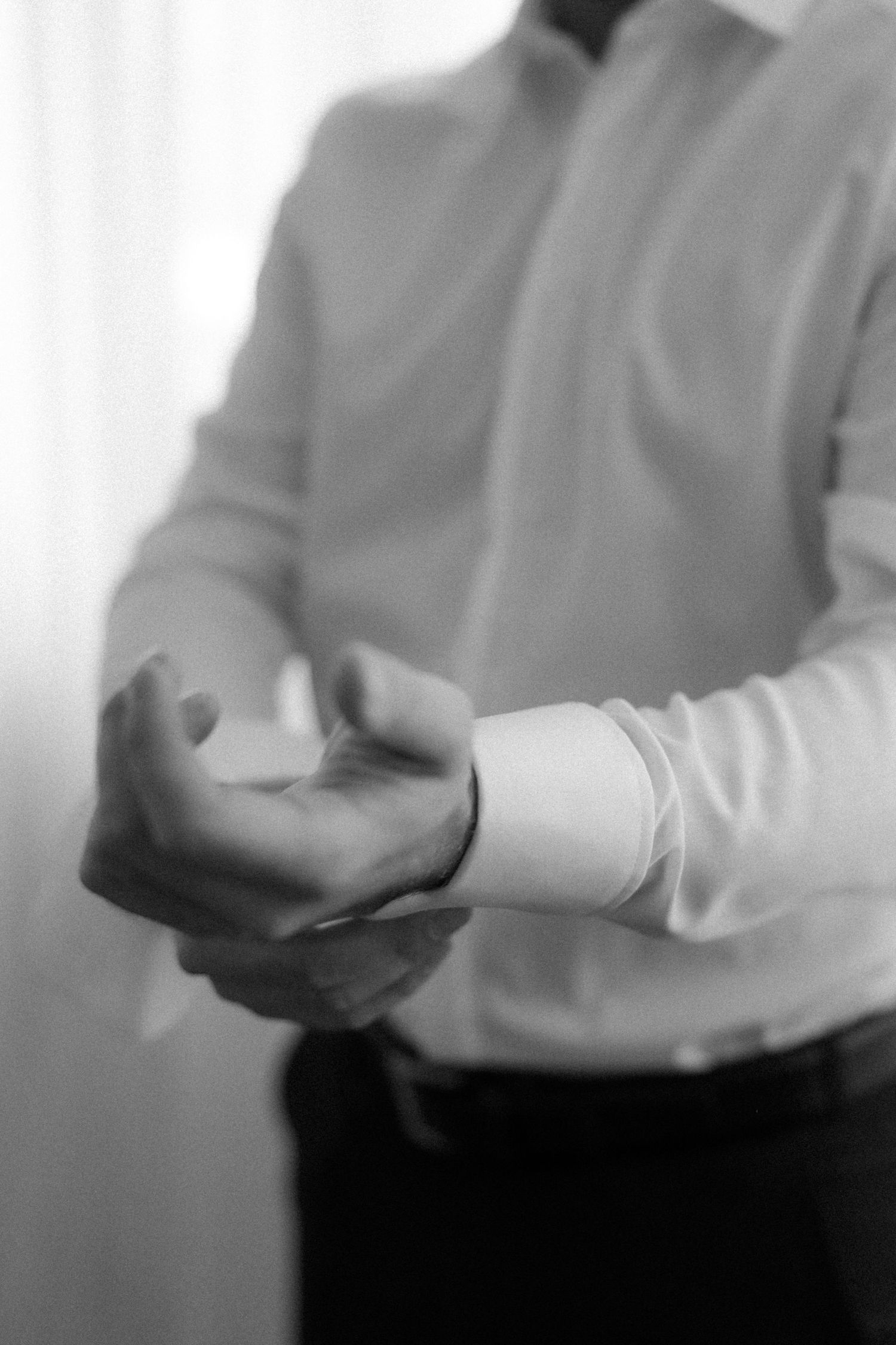 Black and white image of hands adjusting formal wear cufflinks.