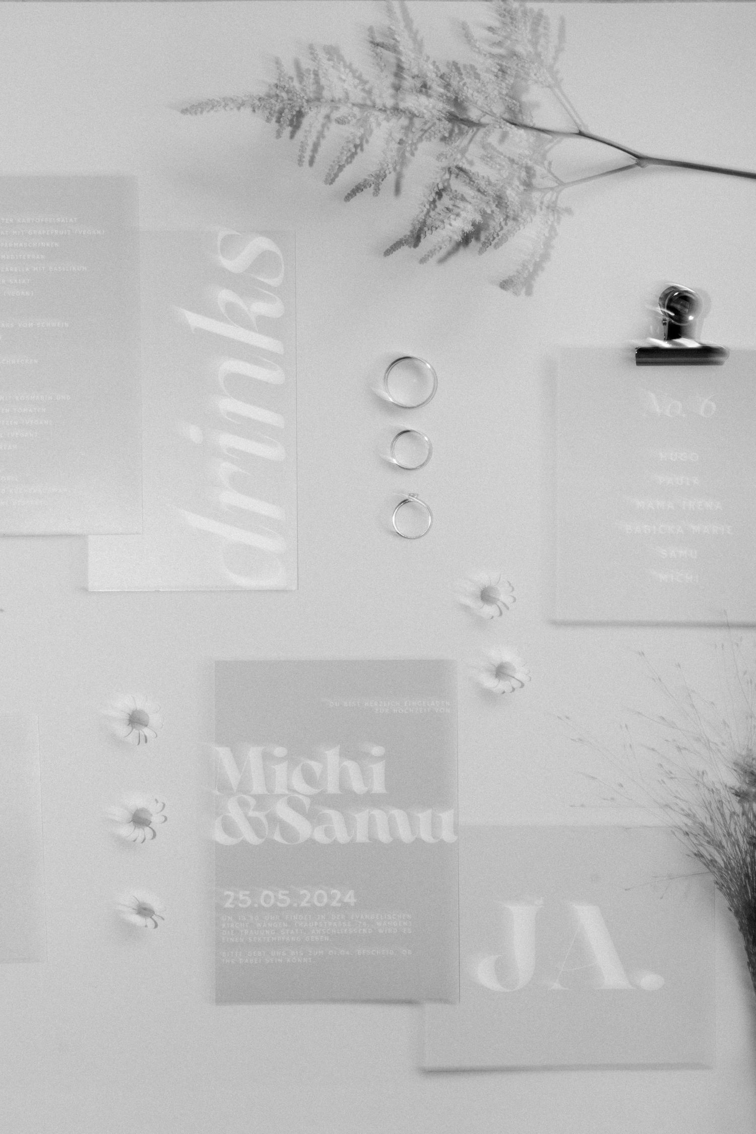 Black and white photo of minimal wedding invitation suite with fern leaves and delicate typography.