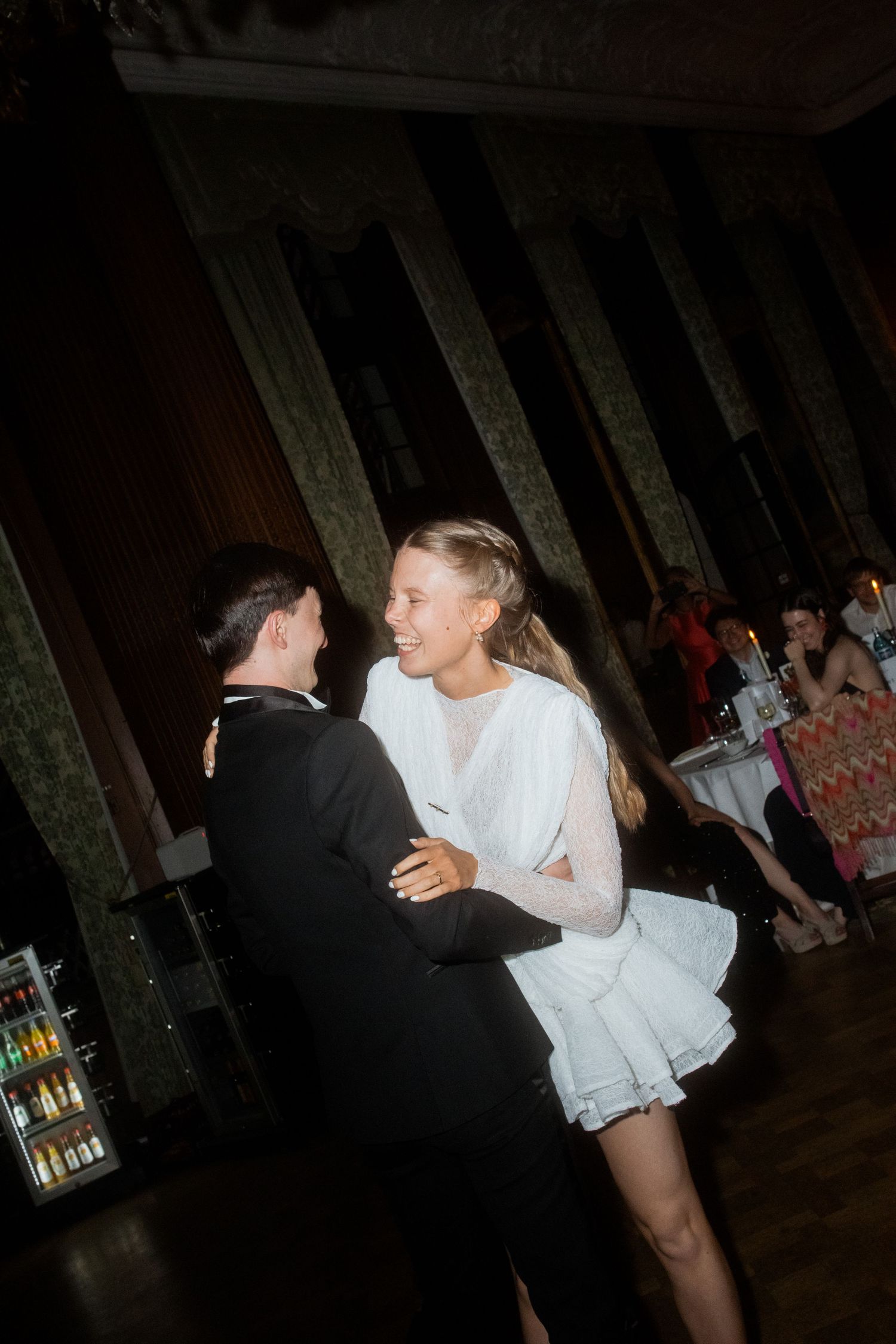 Couple dancing together in formal attire at an elegant venue with vintage decor.