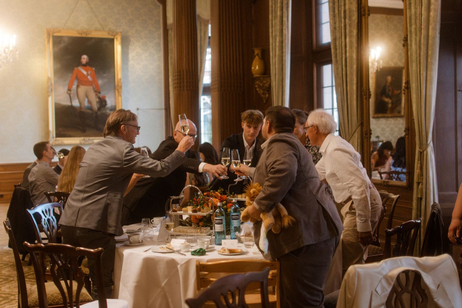 Elegant dining room with vintage portraits and guests gathered around tables for a formal meal.
