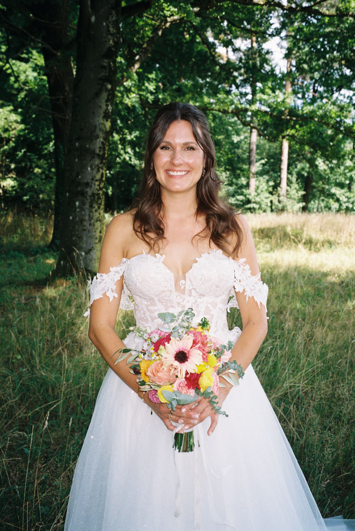 A wedding dress with a colorful bouquet of flowers in a natural outdoor setting.