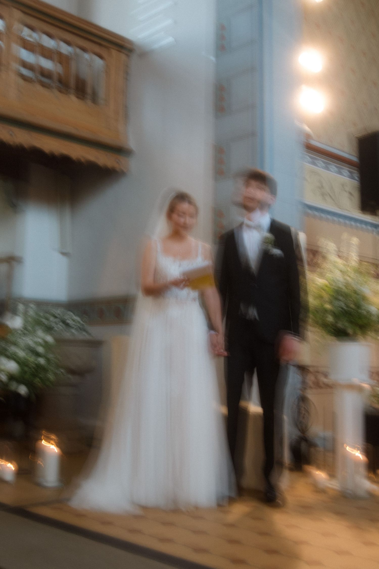 A soft focus photo of a bride and groom standing in church during their wedding ceremony.