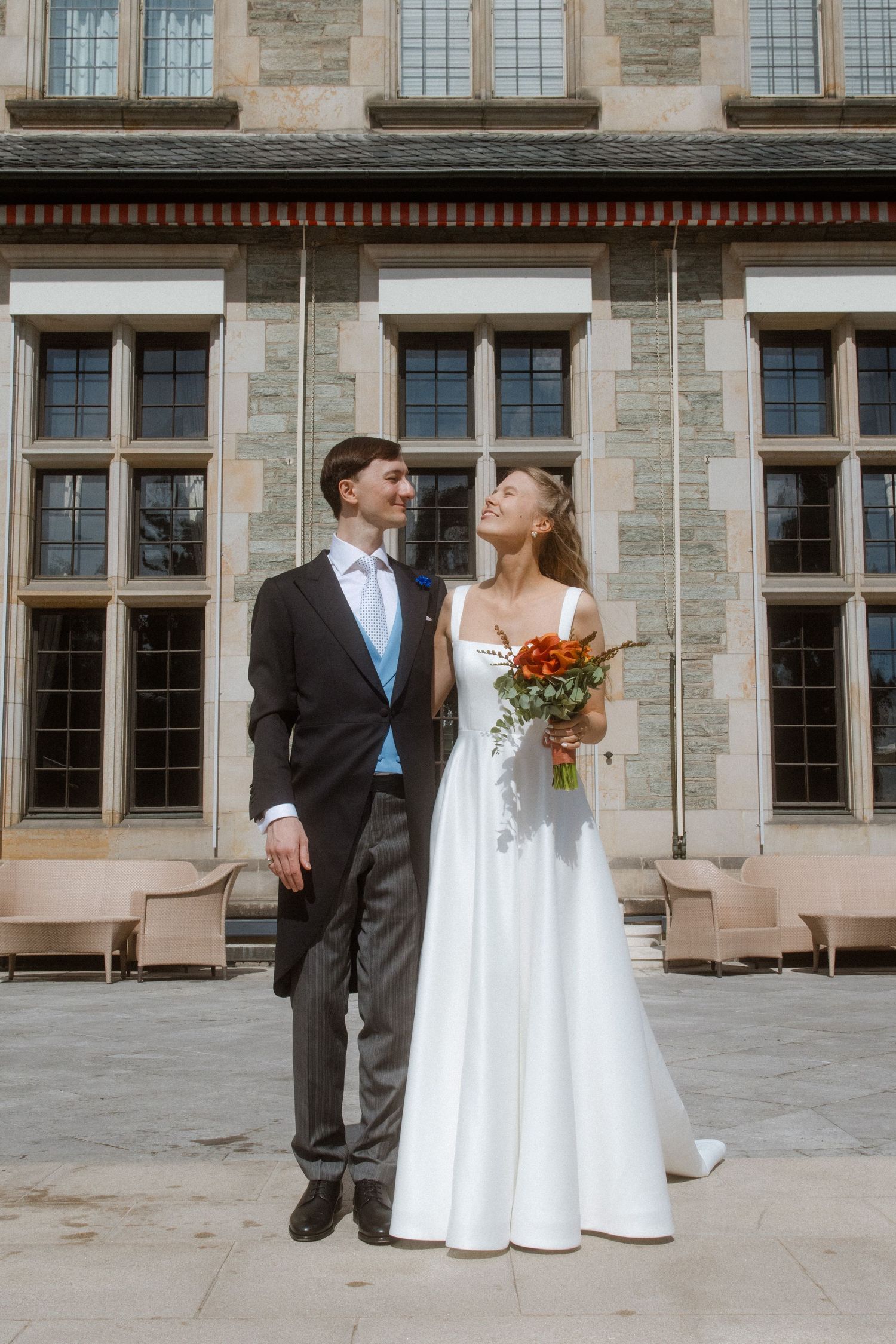 Wedding couple photographed outside a grand stone building with traditional architecture.