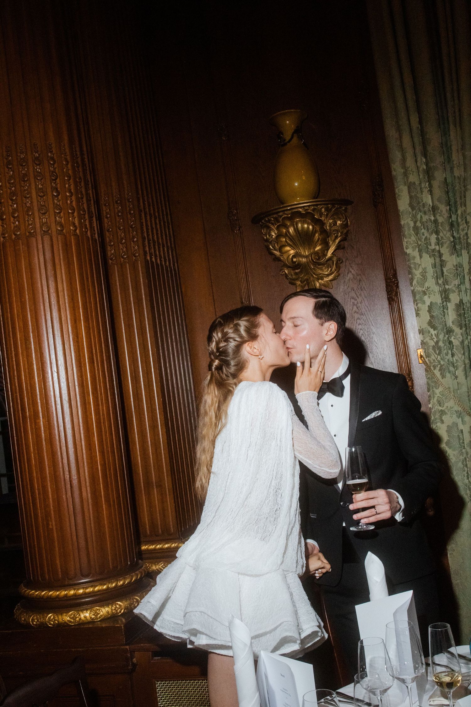 A romantic wedding moment captured in an elegant wood-paneled room with a bride in white.