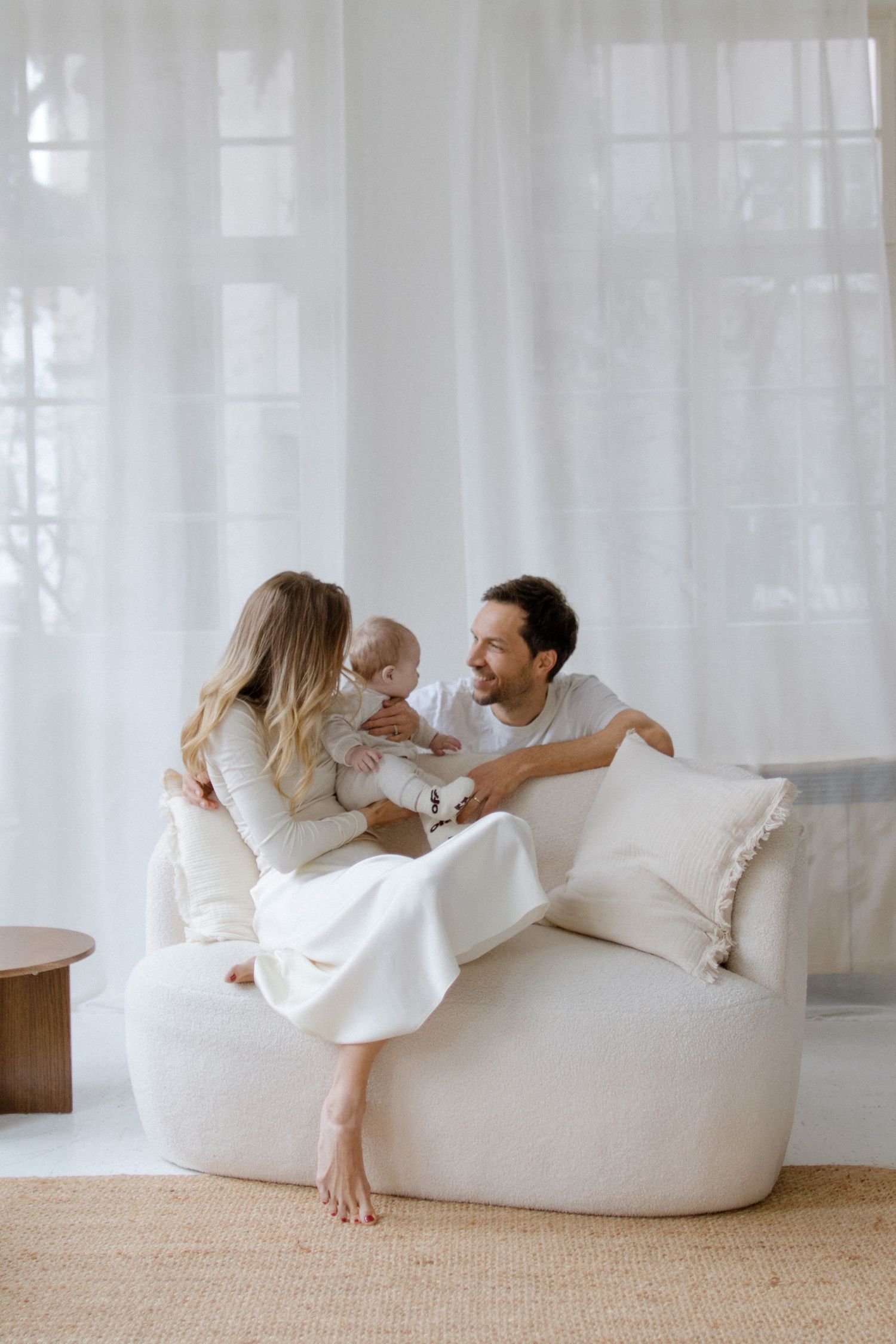 Couple relaxing together on a white bean bag chair in a bright minimalist room.