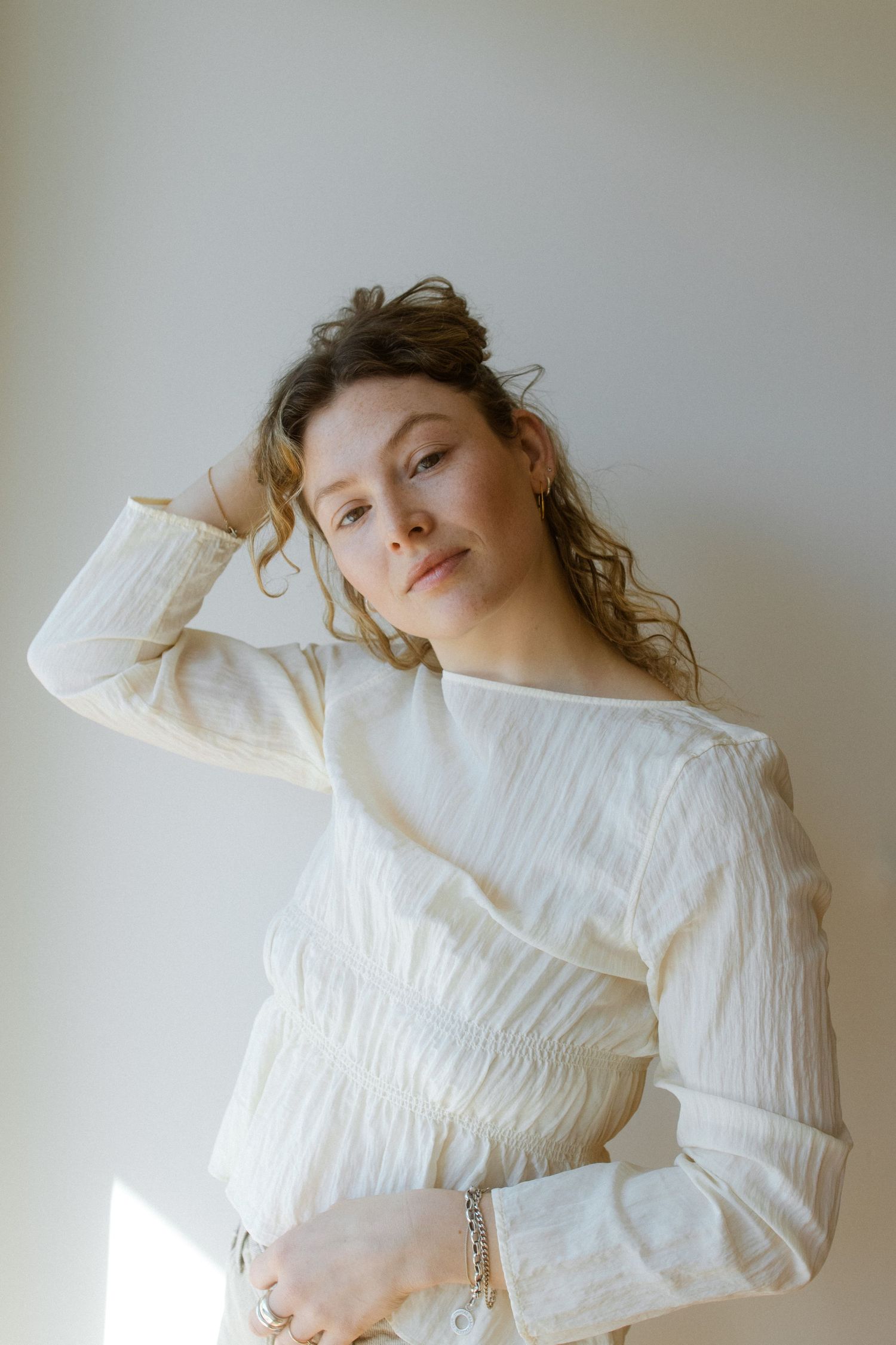 Fashion model wearing a white textured sweater poses against neutral background in artistic portrait series.
