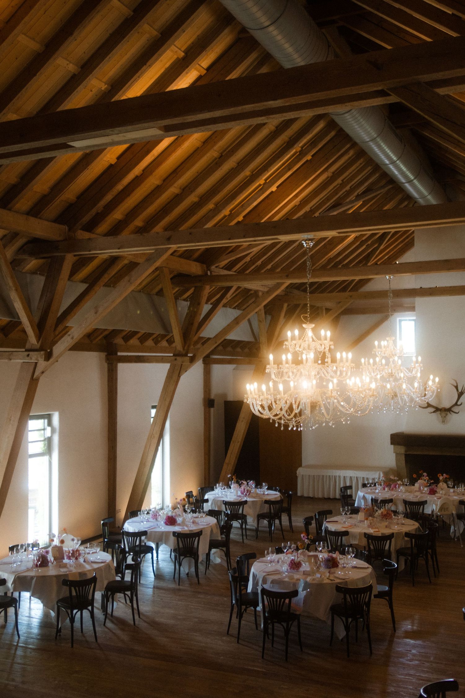 Rustic reception venue with exposed wooden beams and elegant crystal chandelier.