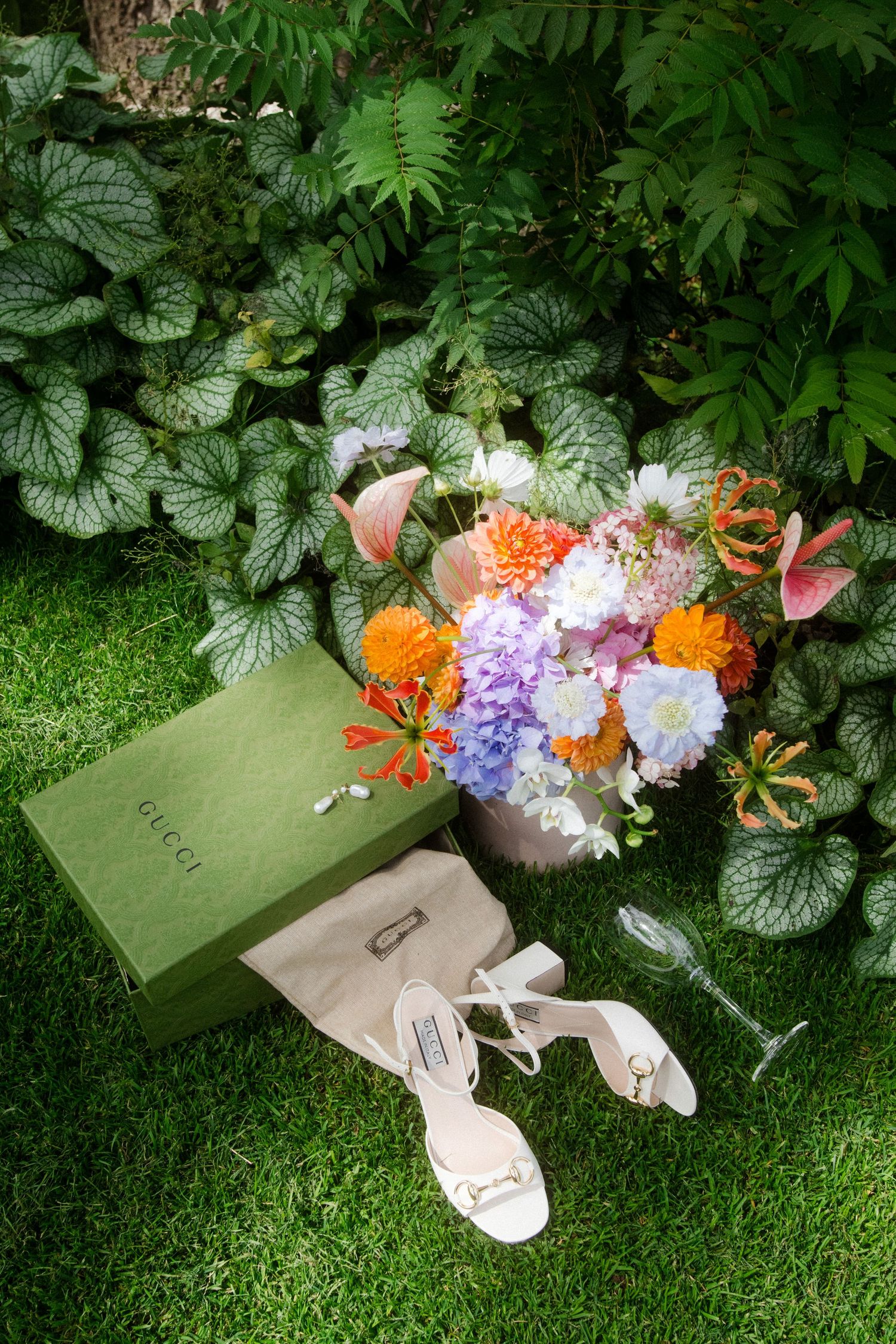 Wedding bouquet with colorful flowers and decorations arranged on green grass.