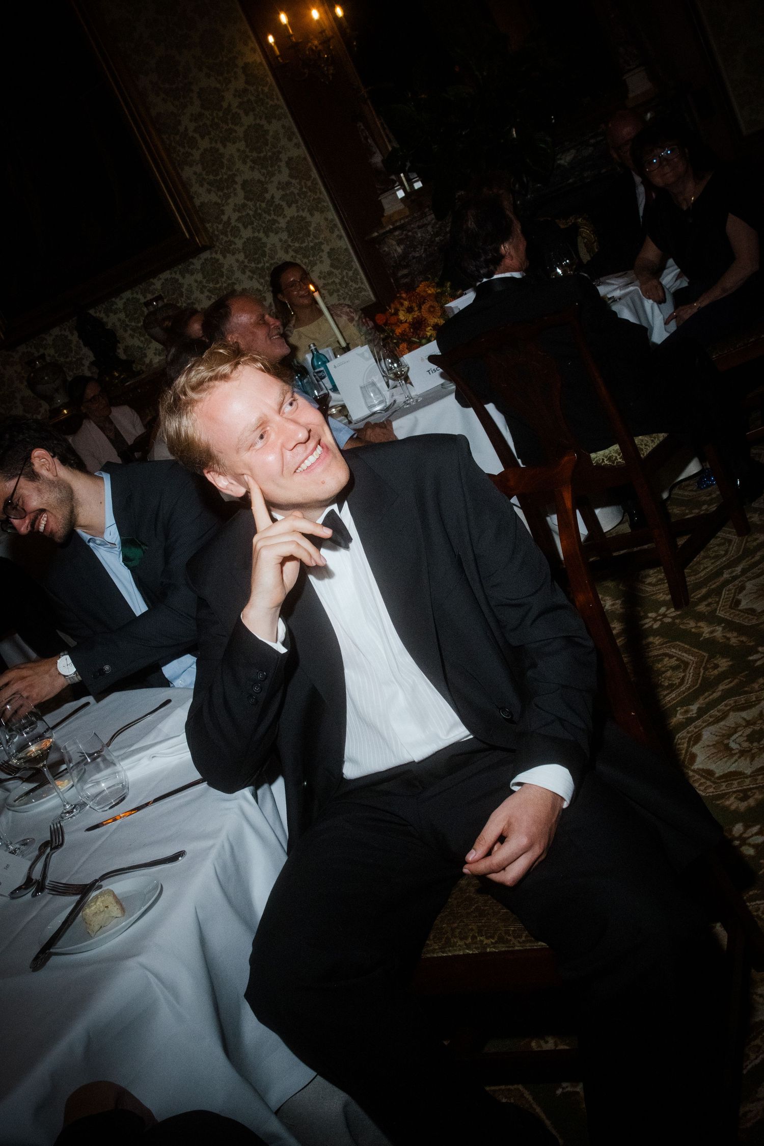 Wedding guests enjoying a candlelit dinner reception in formal attire.