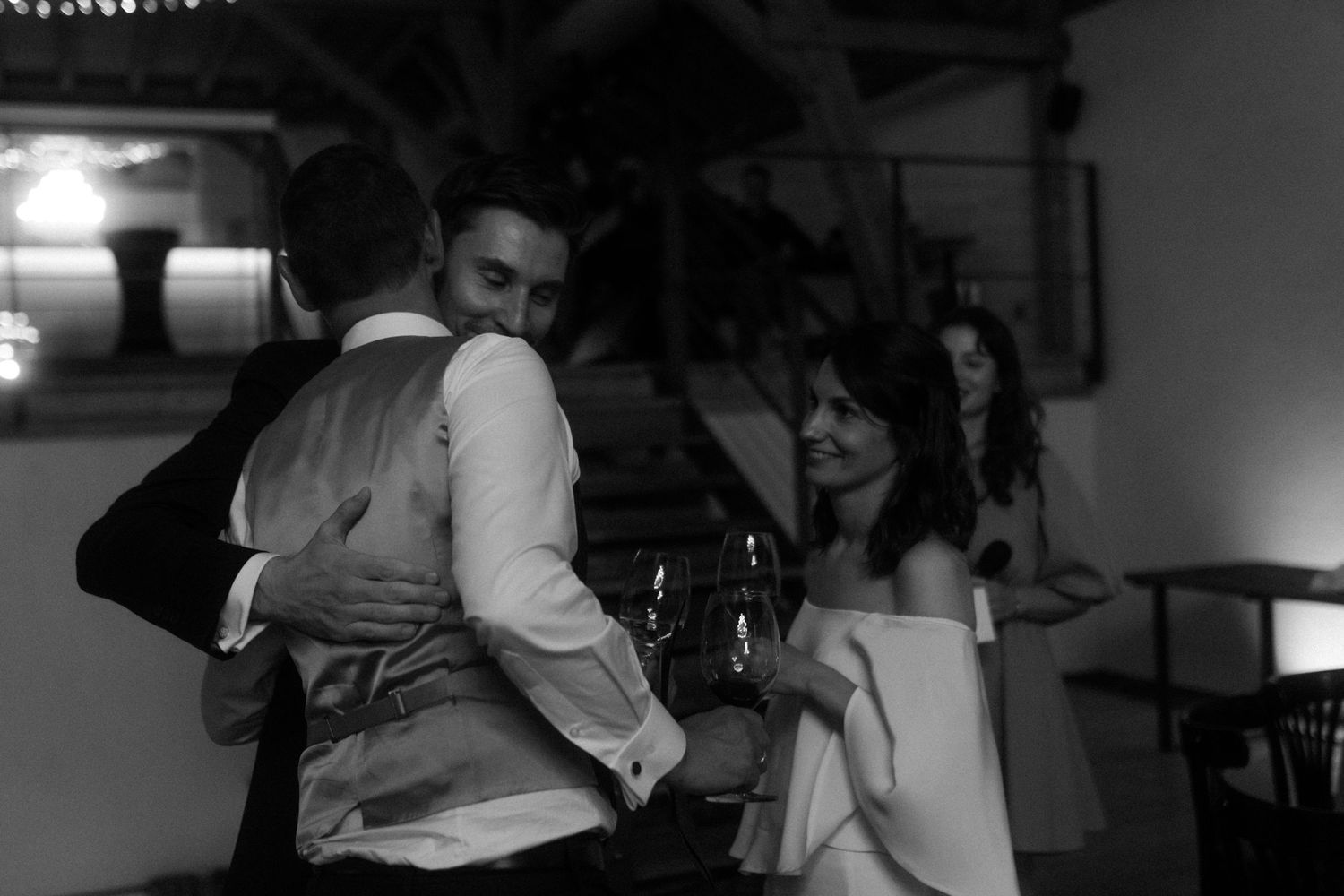 Black and white photo of people at an evening reception in rustic venue.