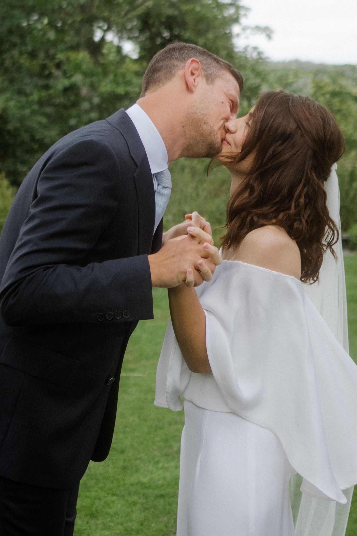 A romantic wedding moment captured as the couple shares a tender kiss while holding hands.