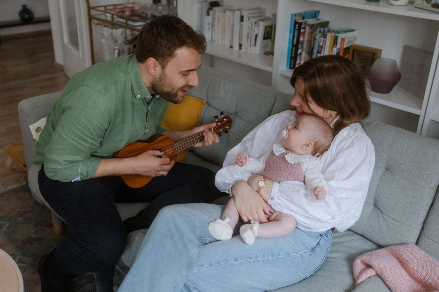 Intimate family moment on couch with acoustic guitar and casual home setting.