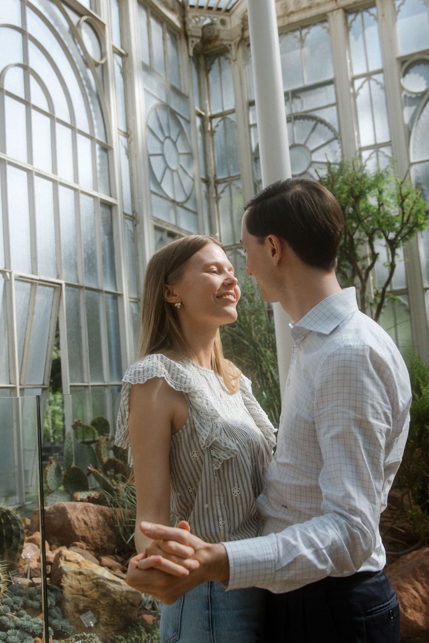 Joyful interaction between couples in a Victorian-style greenhouse with natural light streaming in.