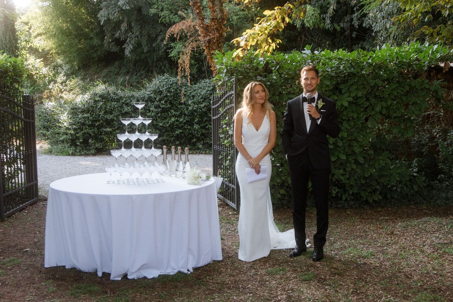 White-clothed reception table with champagne glasses in garden setting.