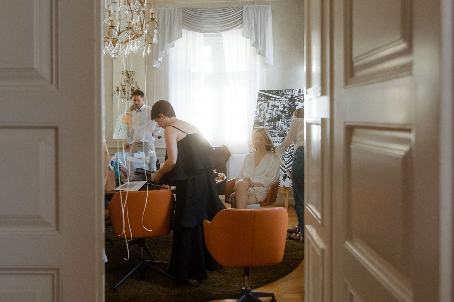 Sunlit room with orange salon chairs and elegant white decor during preparation time.
