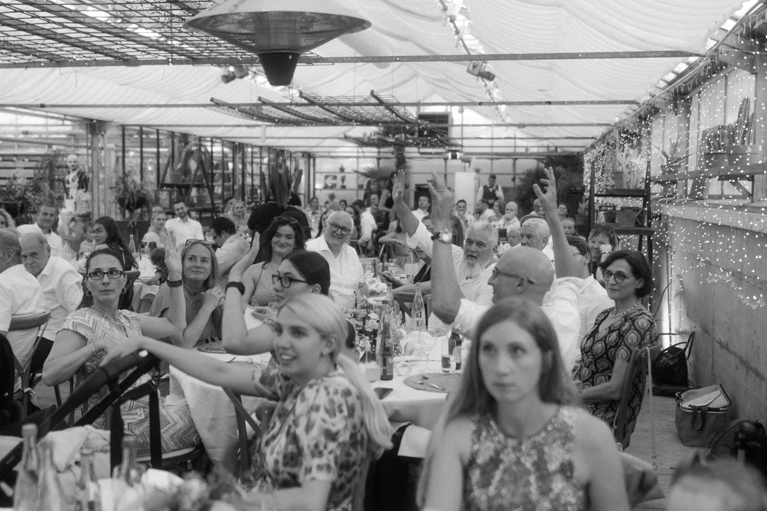Black and white photo of wedding guests enjoying the reception under a tent.