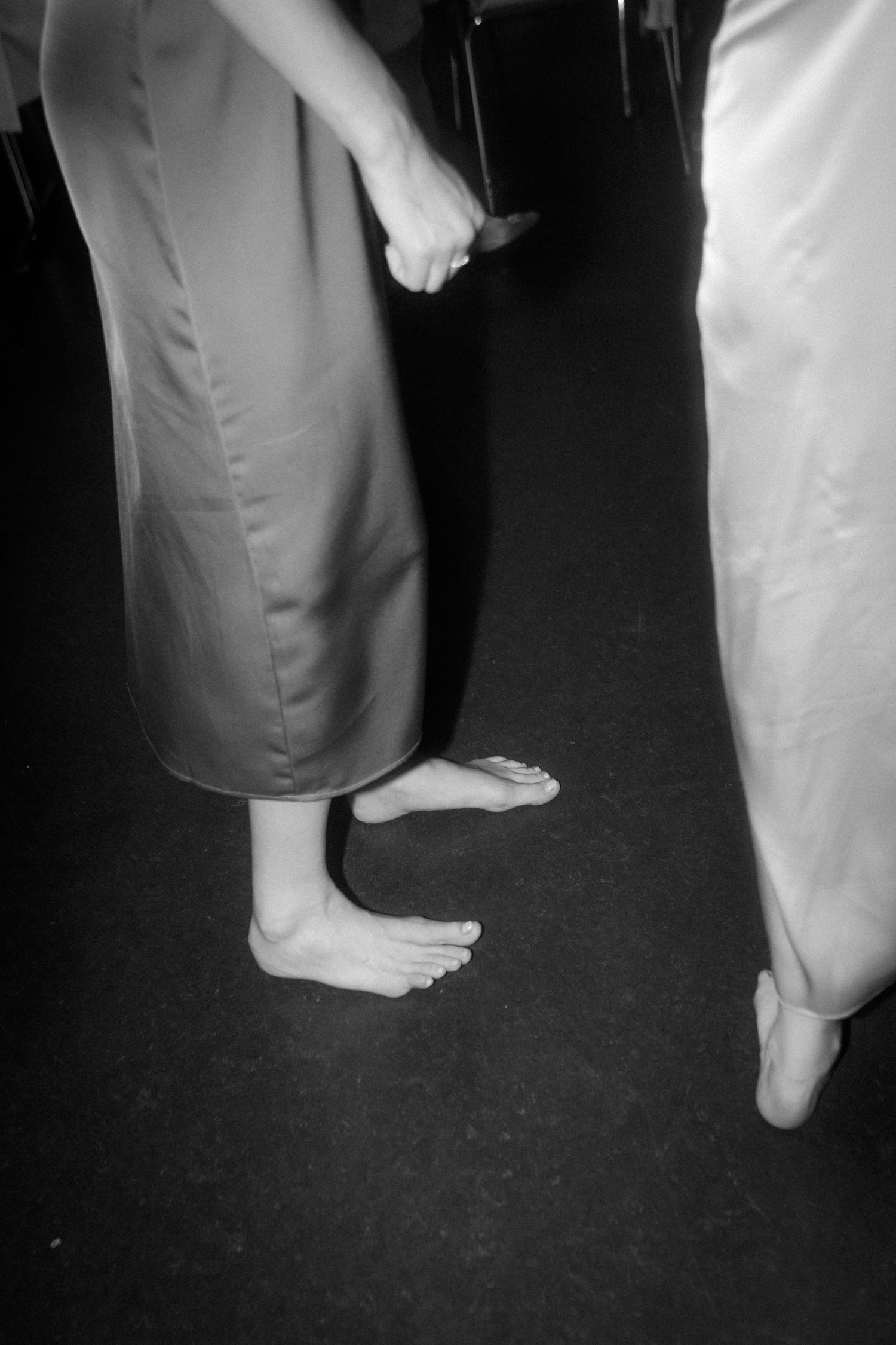Black and white photograph of bare feet and formal attire at a dance or celebration.