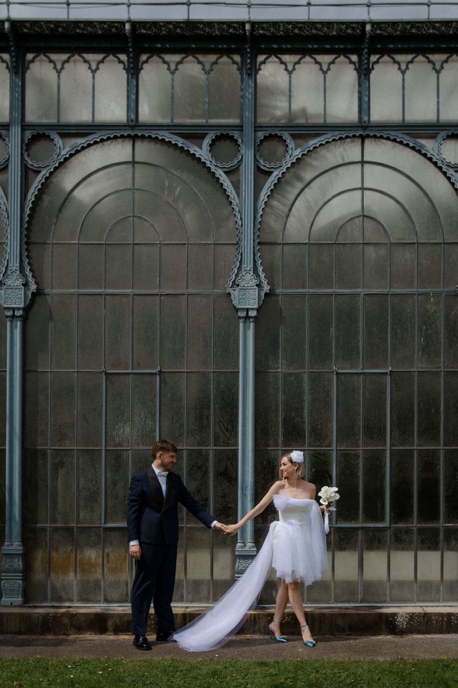 Artistic wedding photo against ornate Victorian glasshouse architecture.
