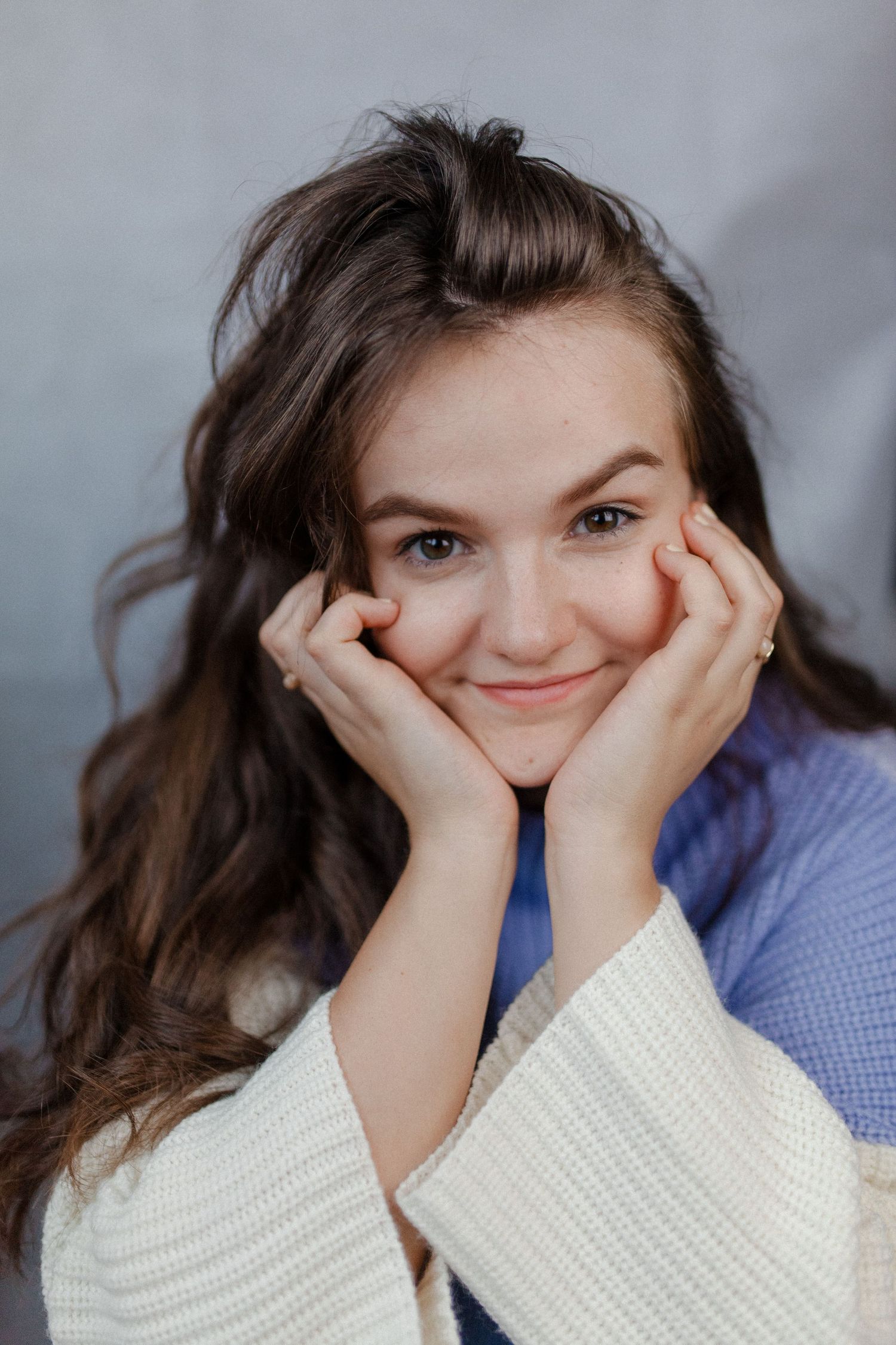 Person in white sweater and blue shirt making playful expressions in a photo series.