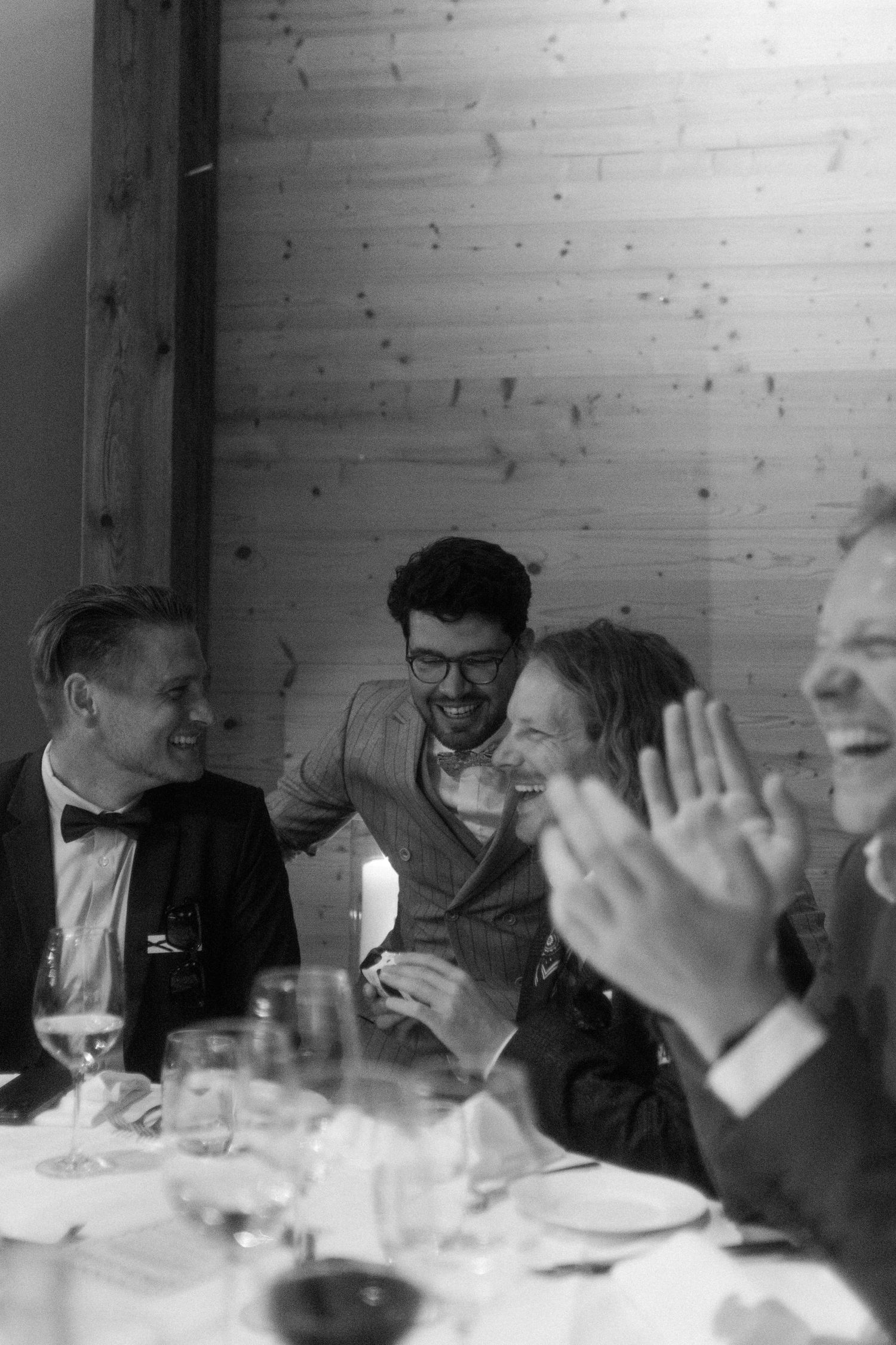 Guests laughing and celebrating at a formal dinner party in black and white photography.