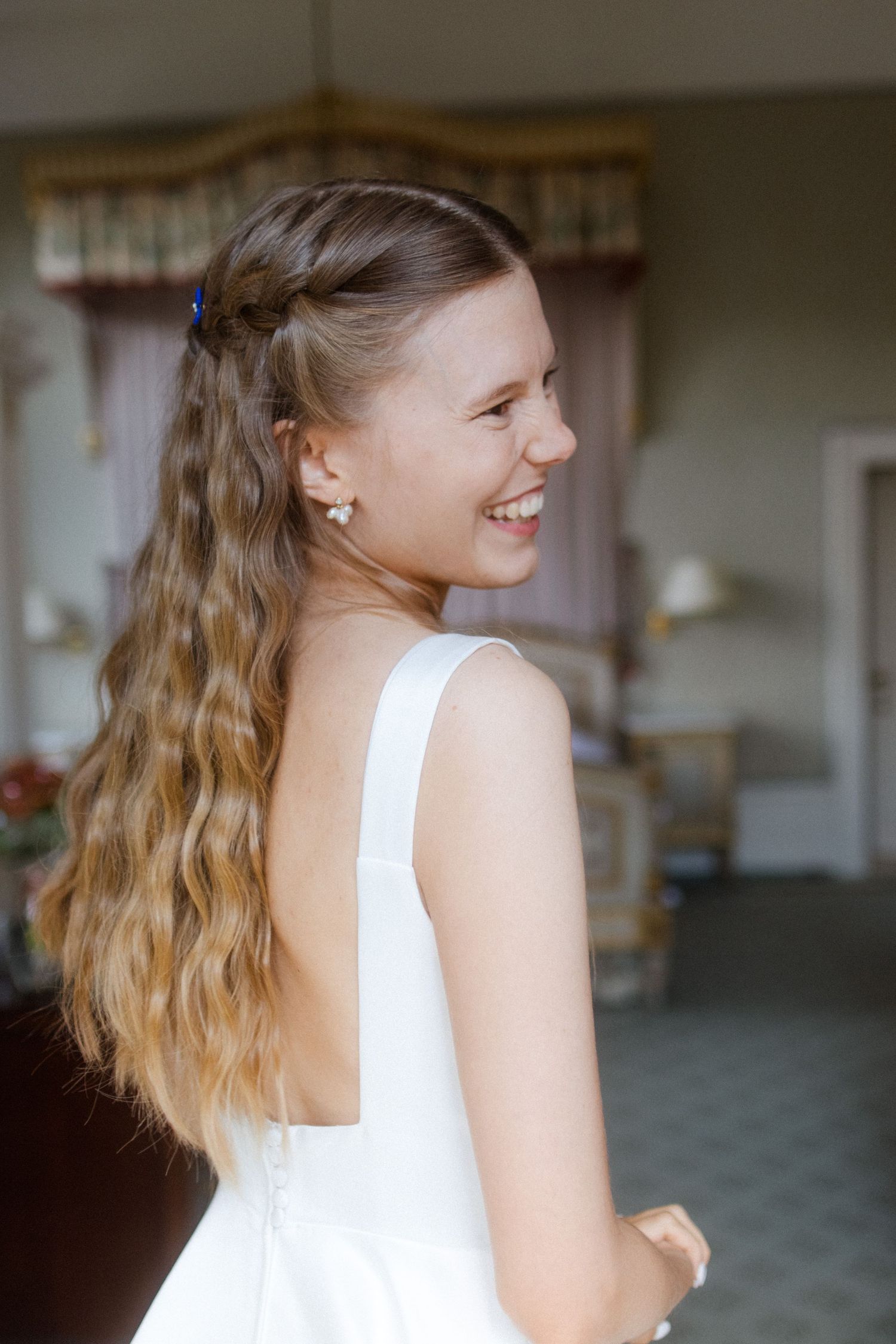 Person in white dress smiling and turning in elegant indoor setting.