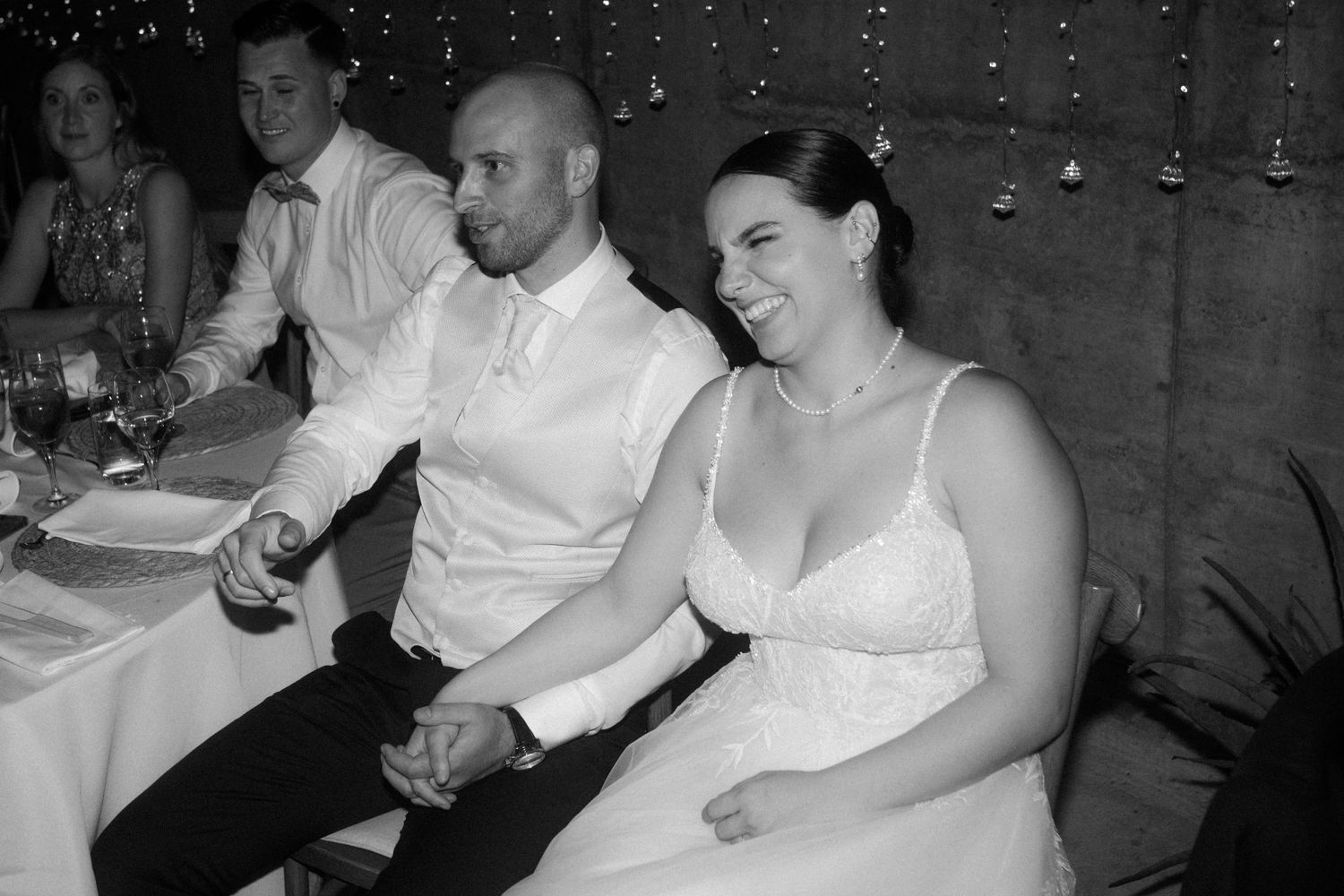 Guests seated at a wedding reception with twinkling lights in the background.