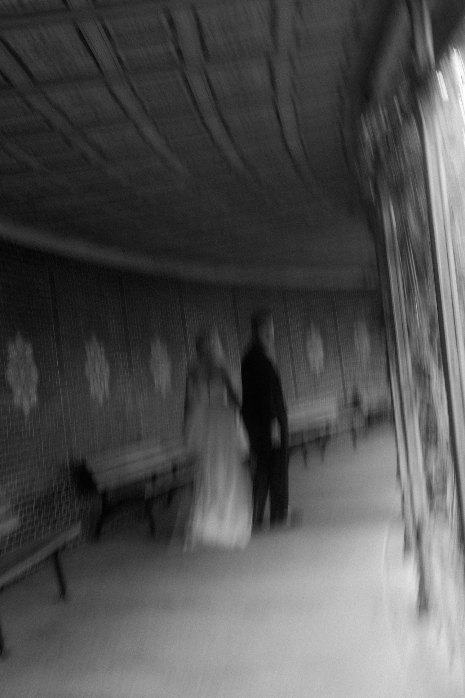 Blurred black and white image of a shadowy figure in a corridor.