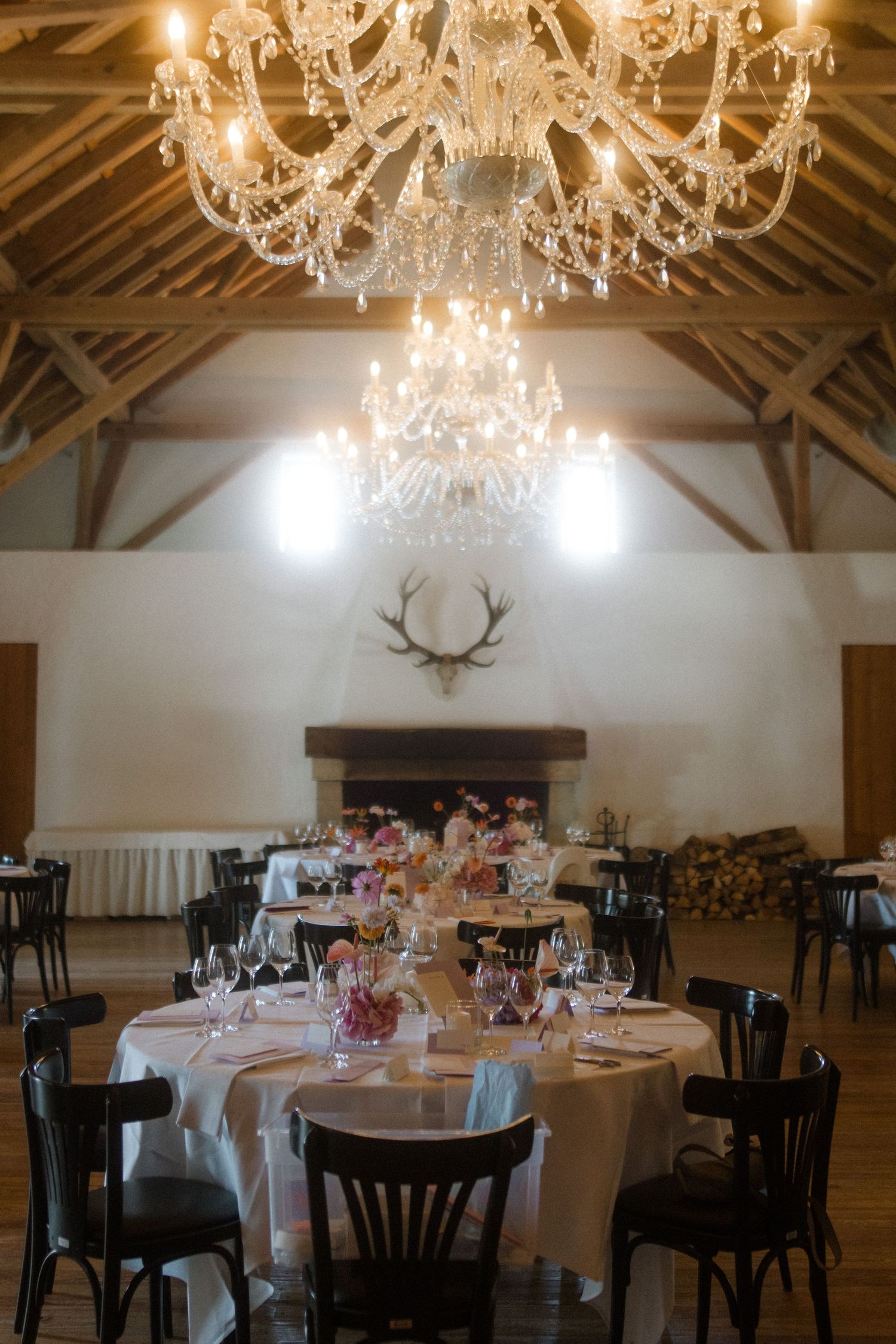 Intimate wedding reception setup with elegant table settings beneath crystal chandeliers.