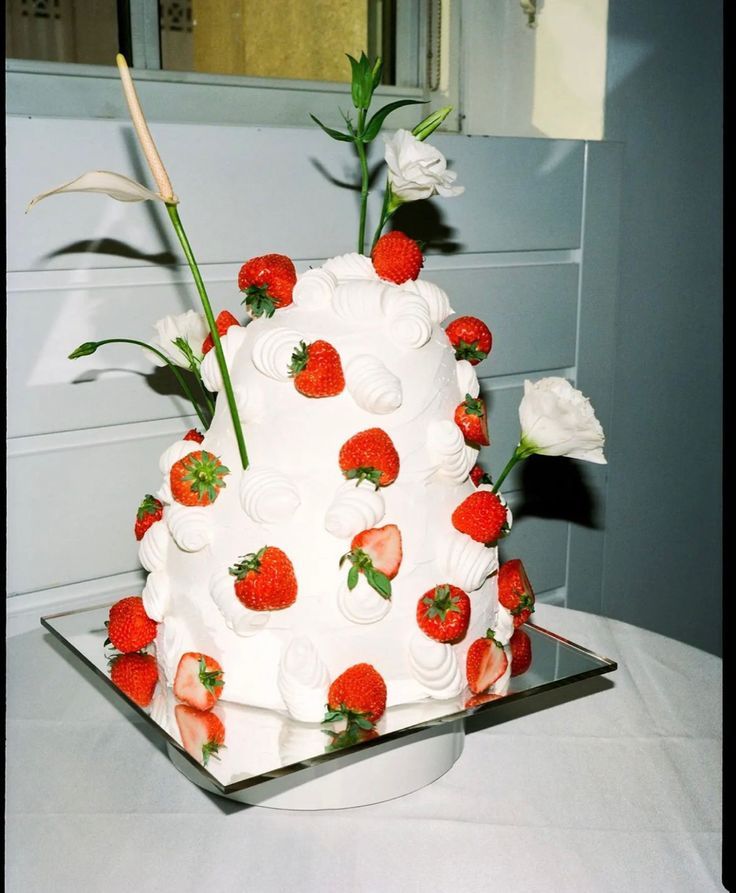 White tiered wedding cake decorated with fresh strawberries and white flowers.