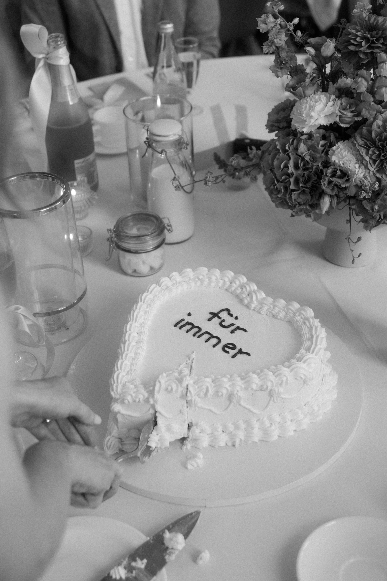 Black and white photo of heart-shaped wedding cake with delicate frosting details.
