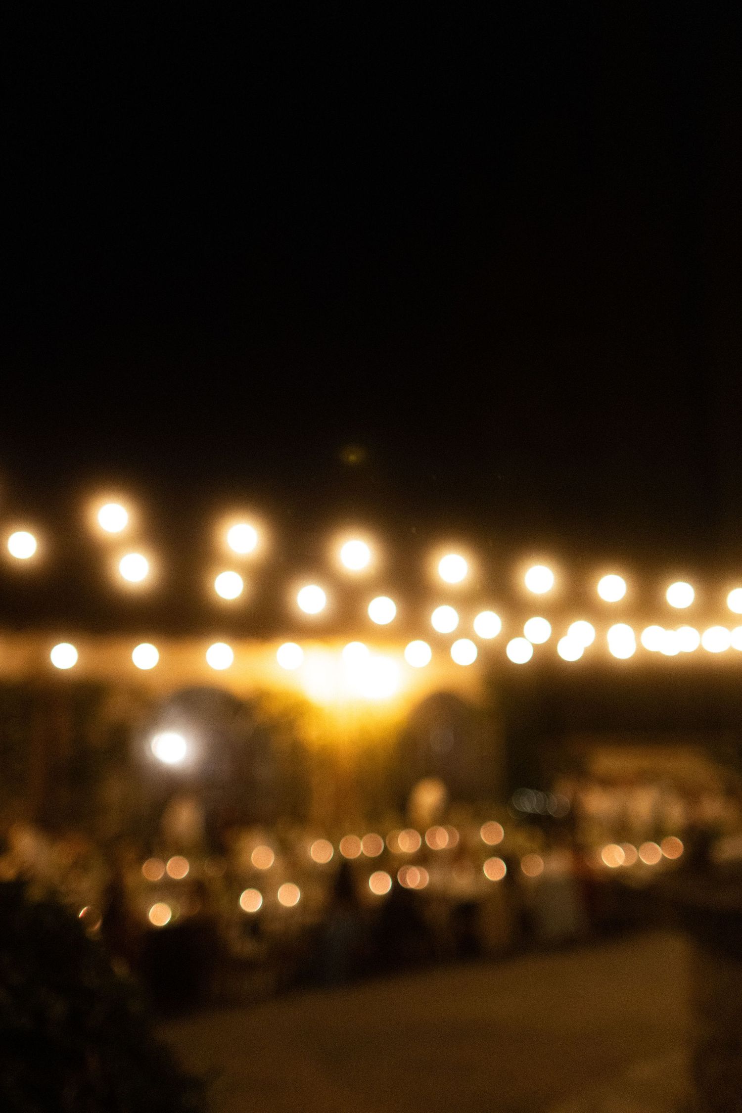 String of warm glowing lights creating bokeh effect against dark night sky.