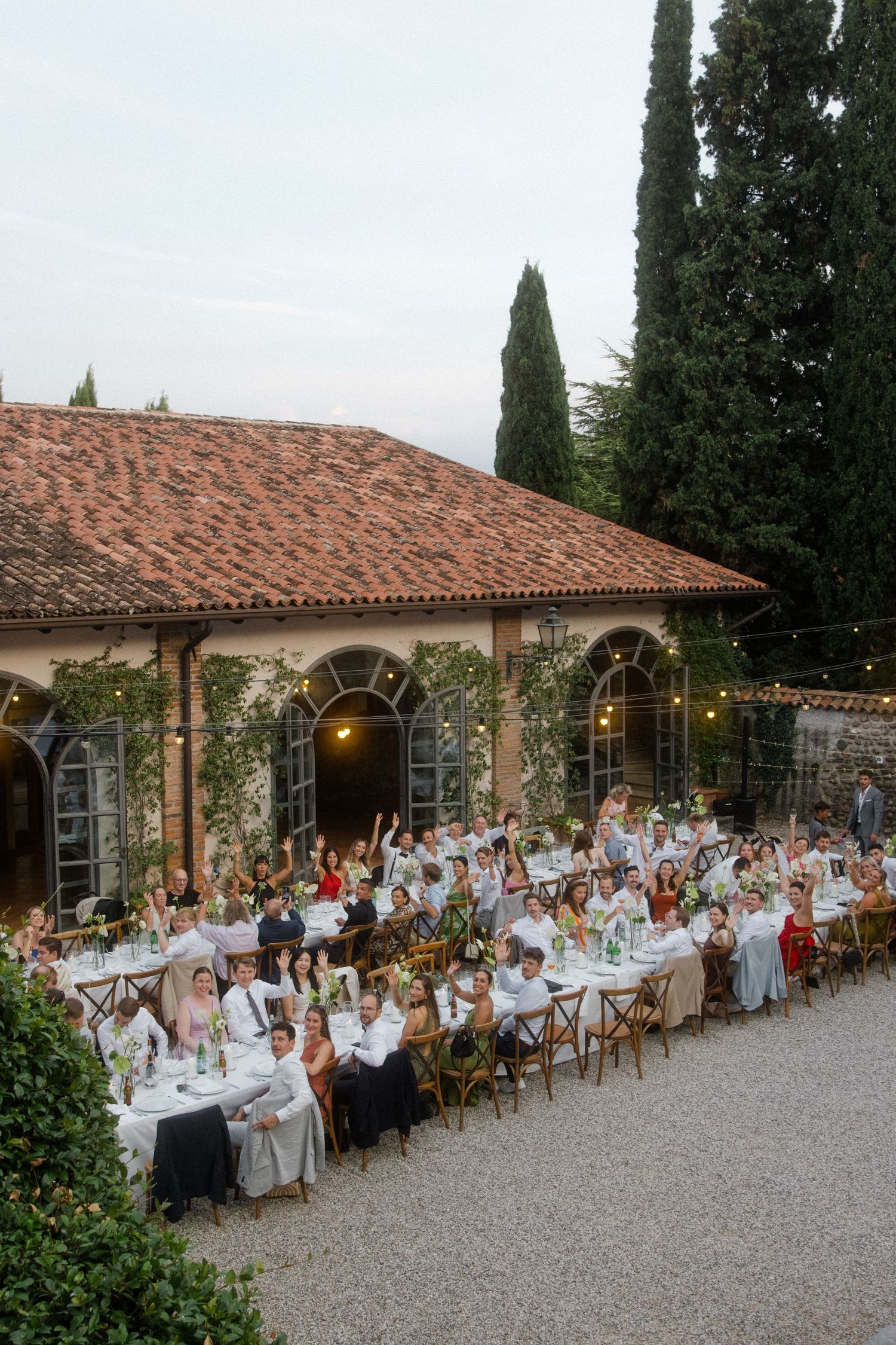 Wedding reception dinner setup along a Mediterranean-style building with terra cotta roof.
