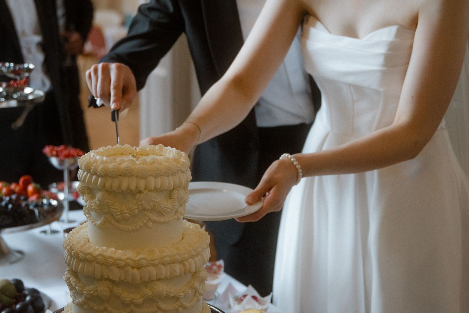 A wedding cake cutting ceremony with white frosted tiers and decorative details.