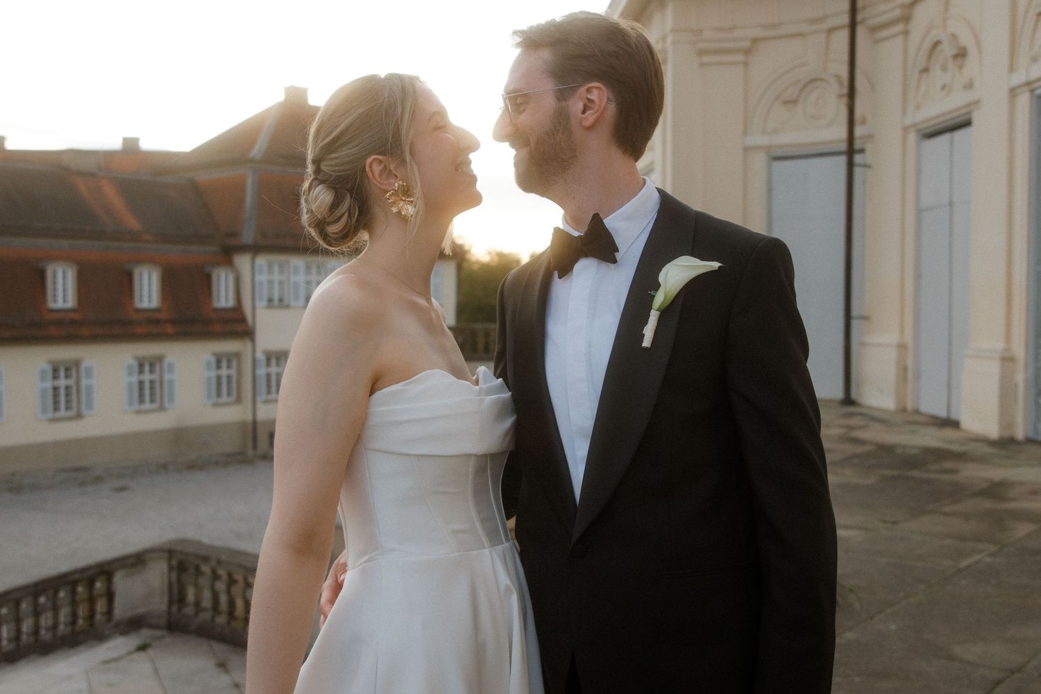 Wedding couple sharing an intimate moment on a grand terrace with classical architecture.