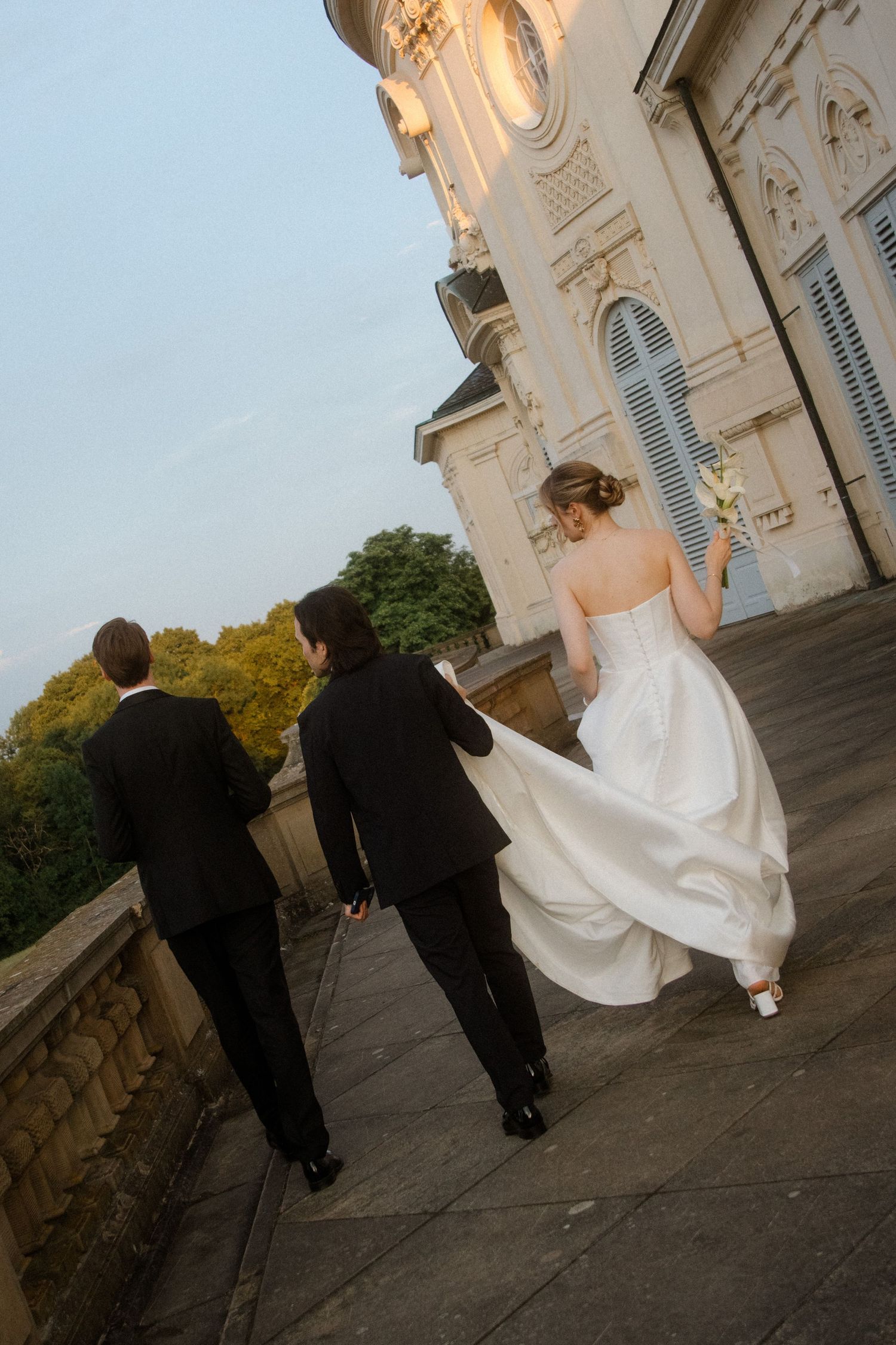 Wedding party walking along a stone pathway at dusk.