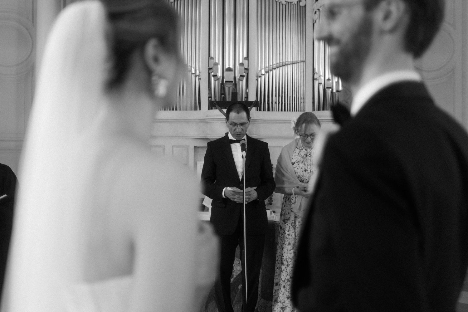 Black and white wedding ceremony photo with church organ pipes in background.